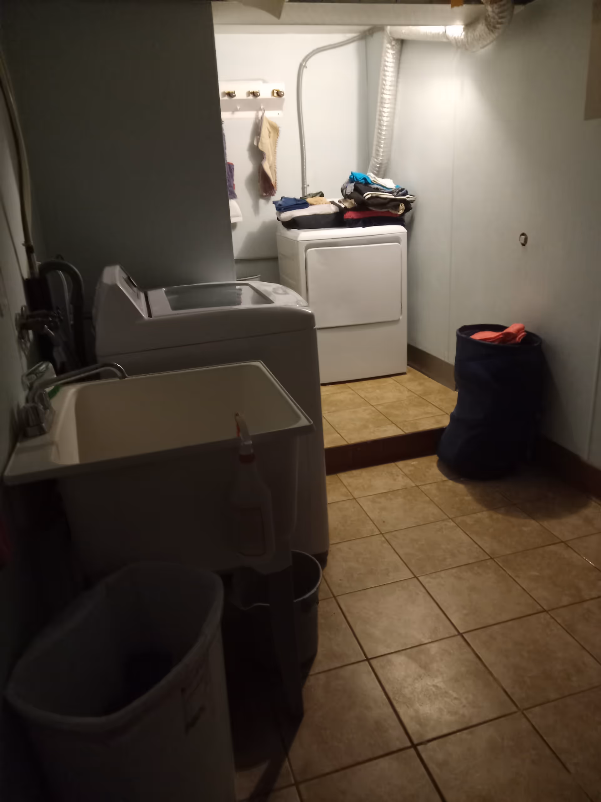 Small laundry room with a washing machine, dryer, sink, and laundry basket.