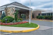 Front exterior of Carillon Nursing and Rehabilitation Center with stone entry and manicured landscaping.