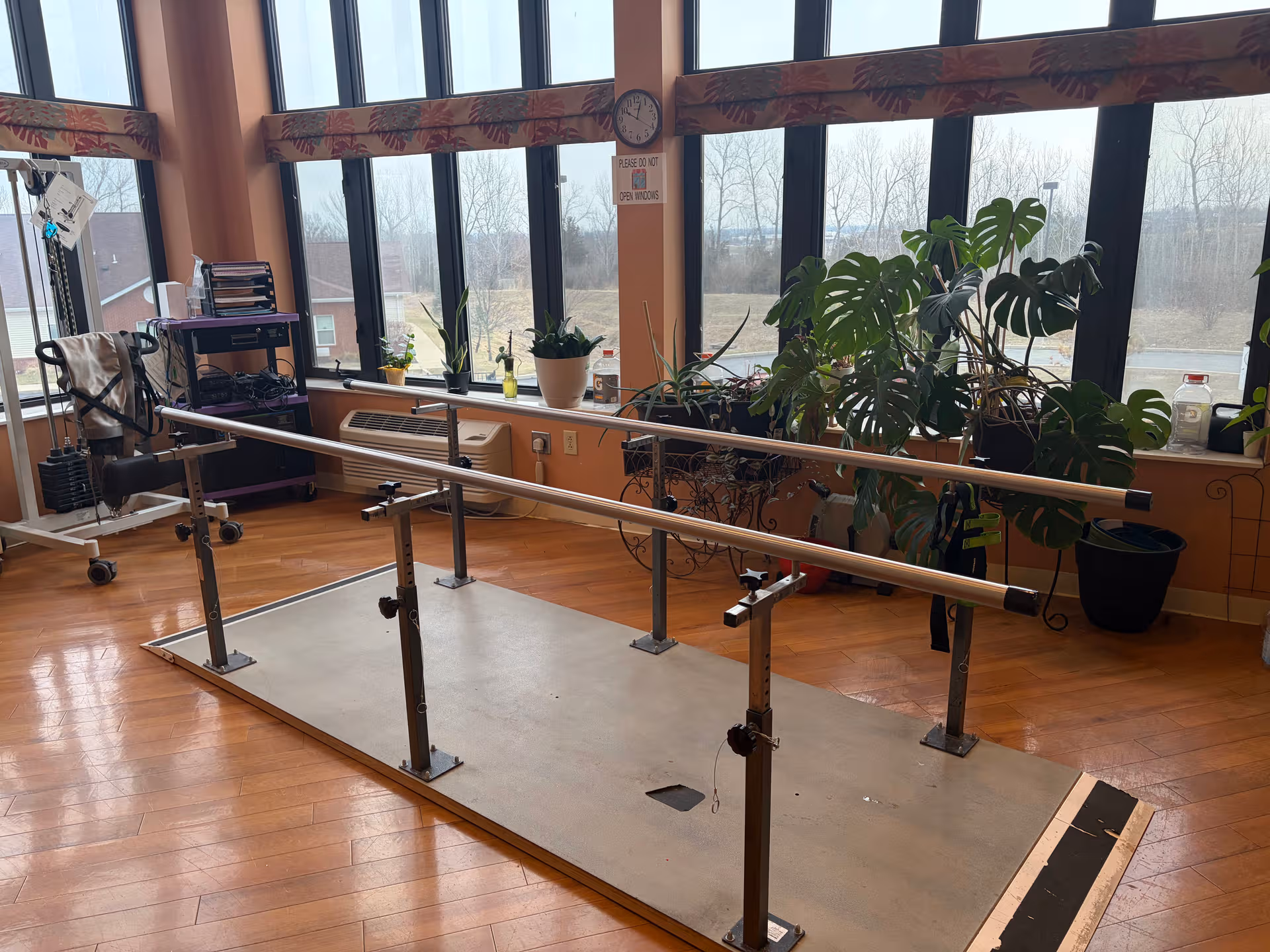 Therapy parallel bars on a raised platform inside a bright rehab room.