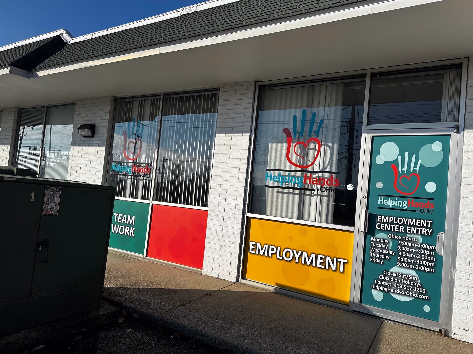 Exterior view of Helping Hands of Ohio storefront with employment and team-work signage.