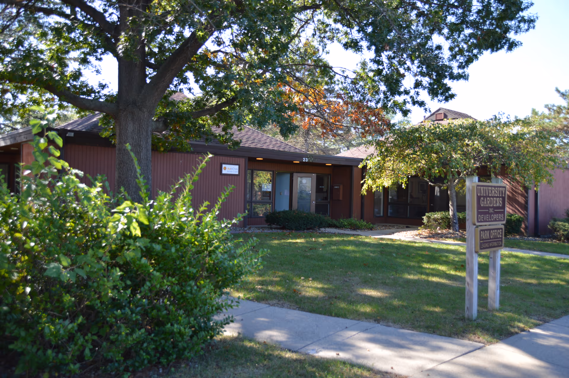 Exterior view of a brown single-story building entrance with trees and a sidewalk