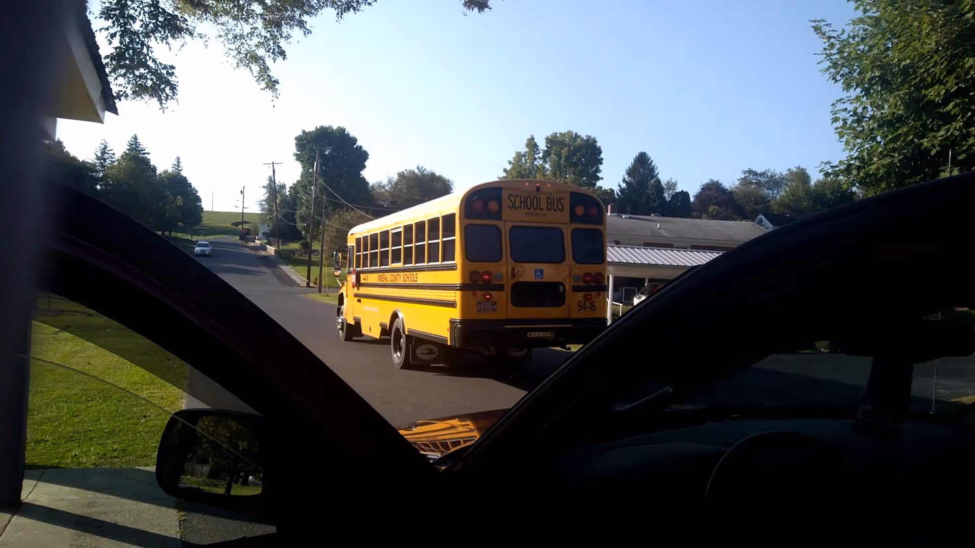 Yellow school bus driving on a street as seen from inside a car.