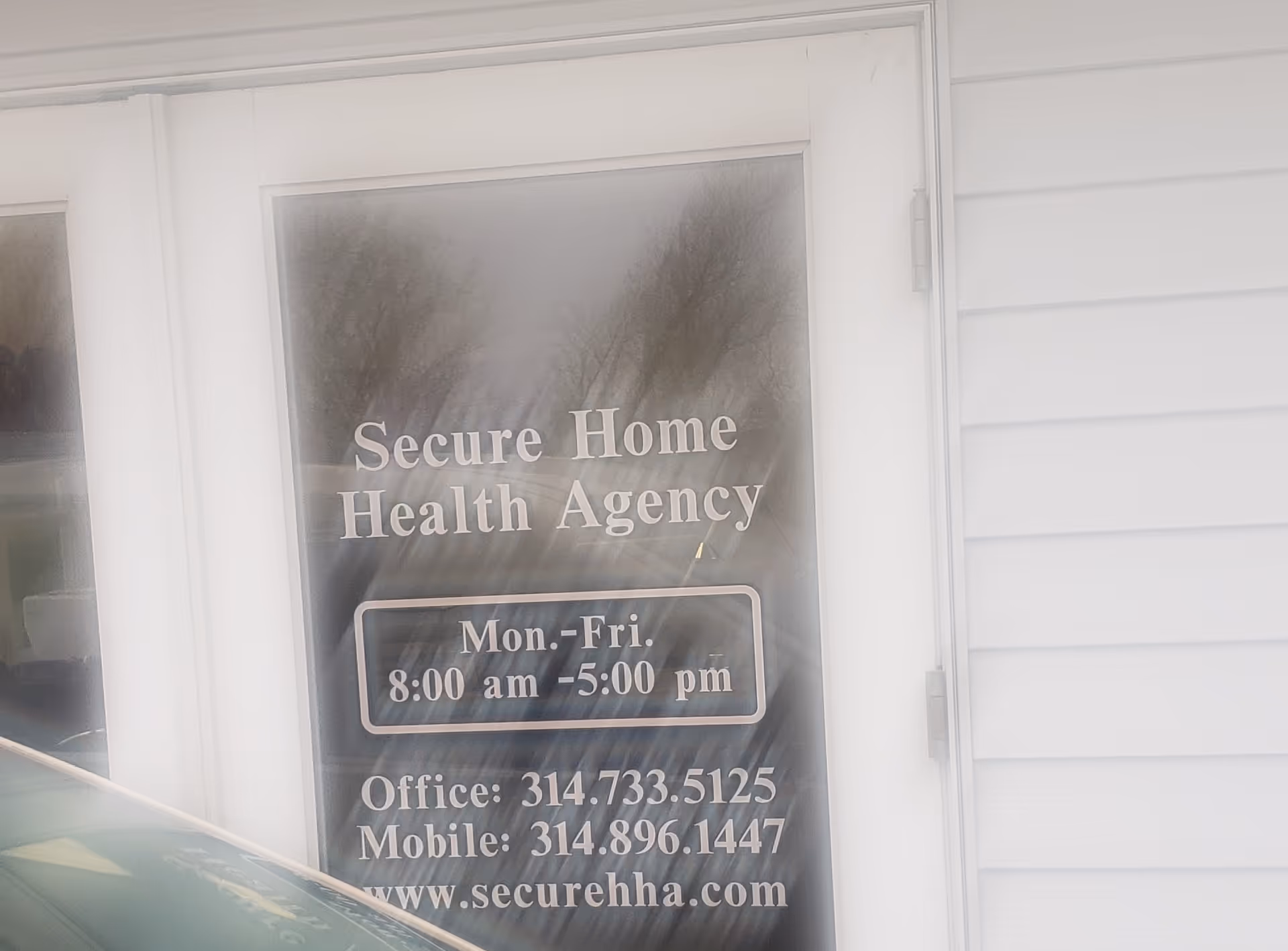 The front entrance of Secure Home Health Agency with a glass door showing office hours.