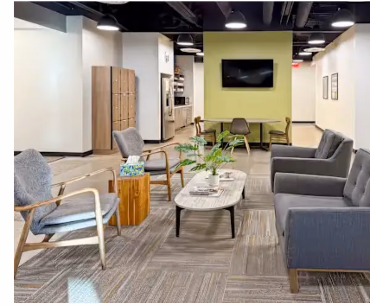 Modern senior living lounge with seating, a coffee table, and a wall-mounted TV.