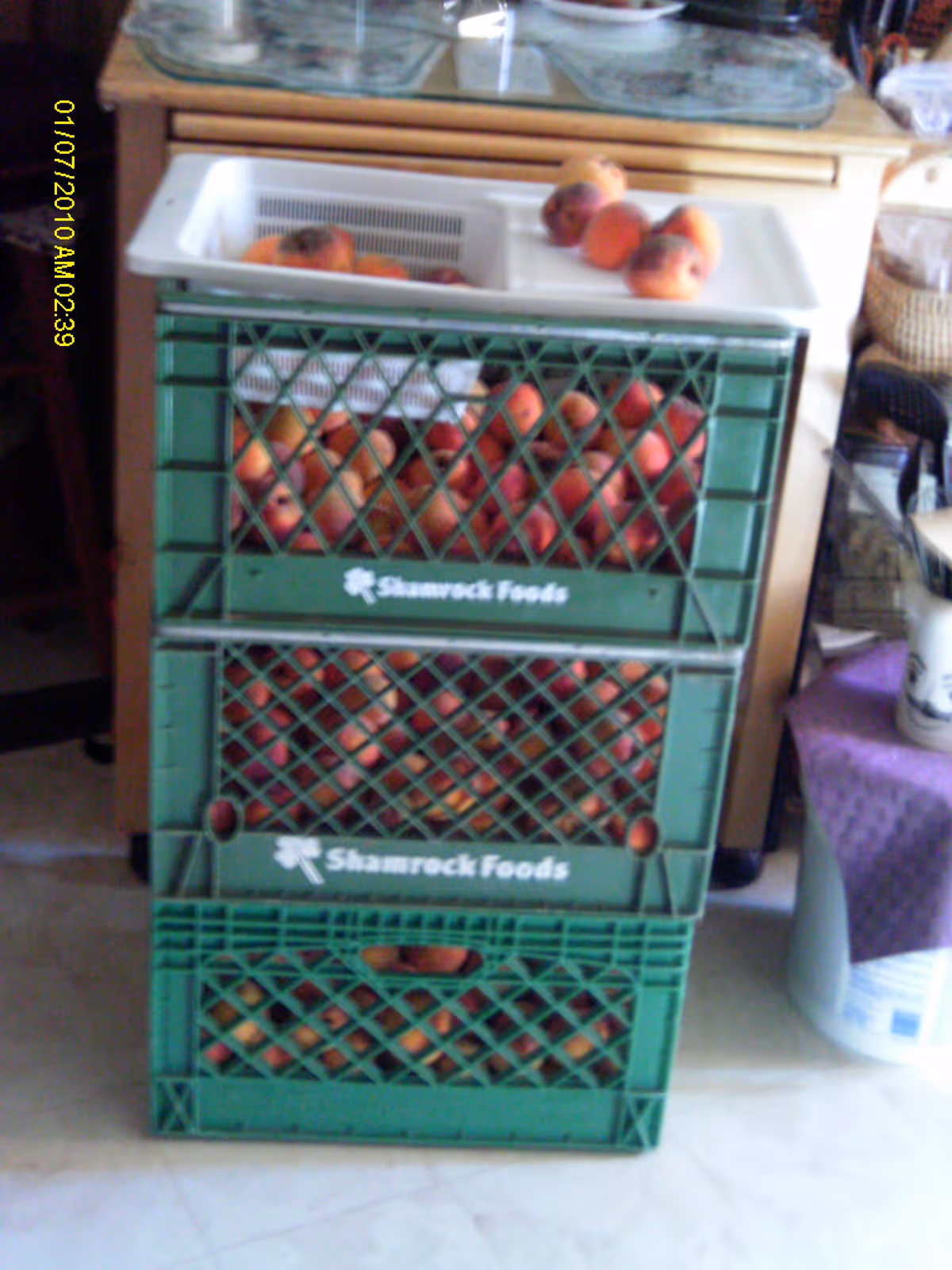 Green Shamrock Foods crates filled with peaches stacked in a kitchen.