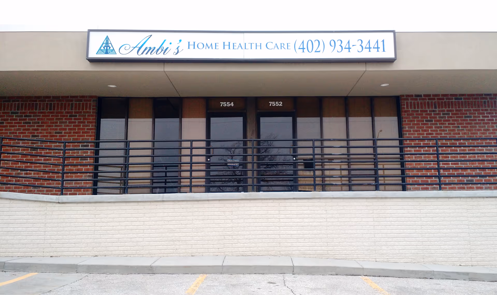 Brick storefront with Ambi's Home Health Care sign, glass doors, and railing.