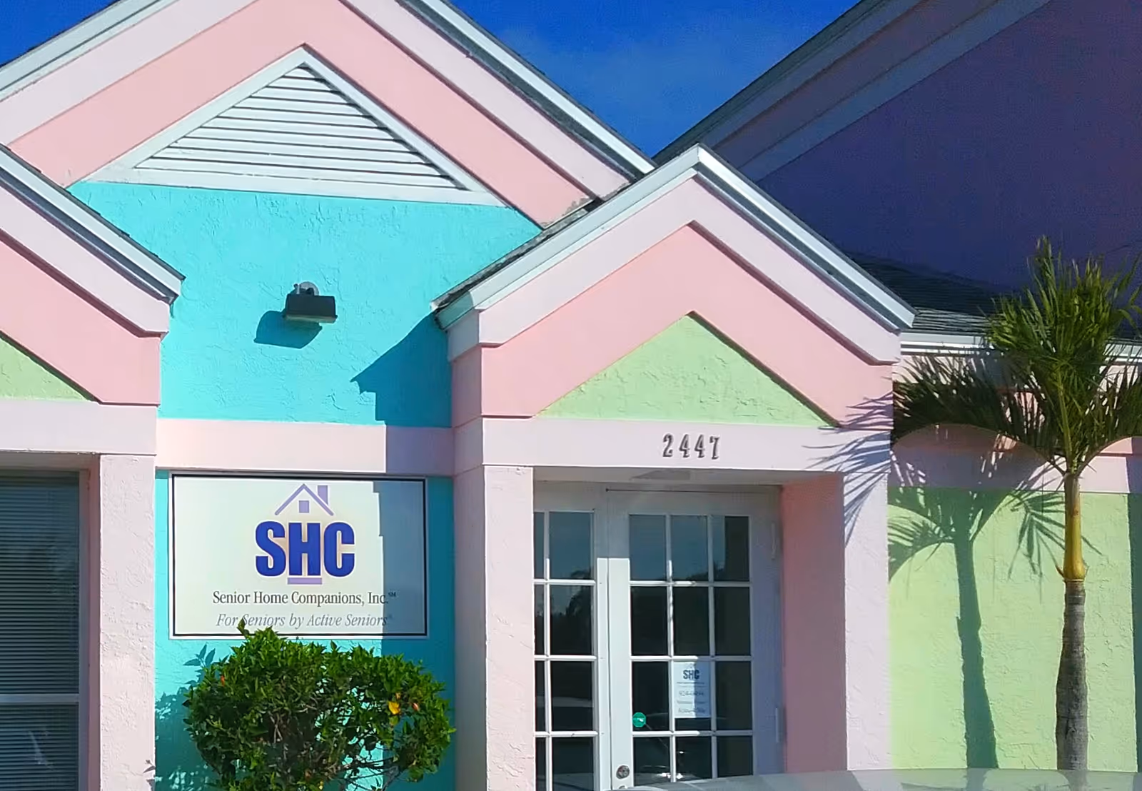 Pastel-colored senior home entrance facade with SHC sign and glass doors.