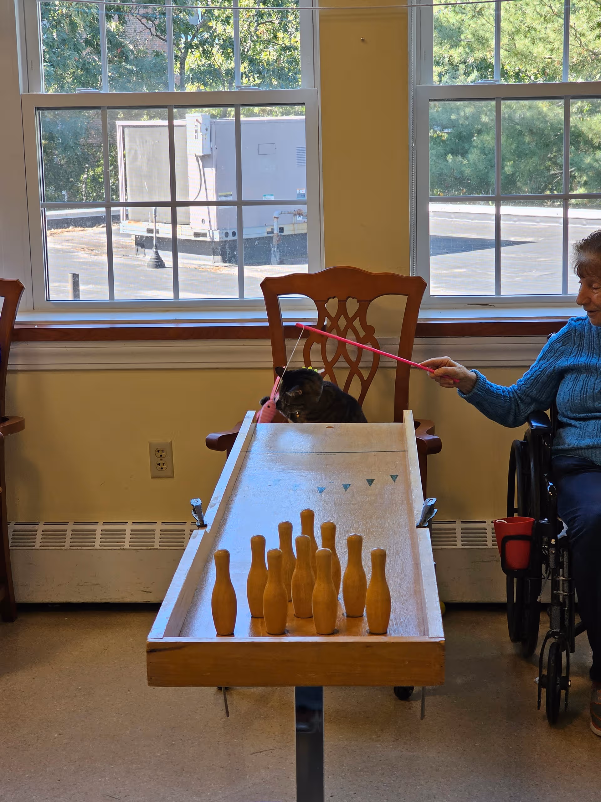 Senior in a wheelchair participates in a bowling game with a ramp indoors.