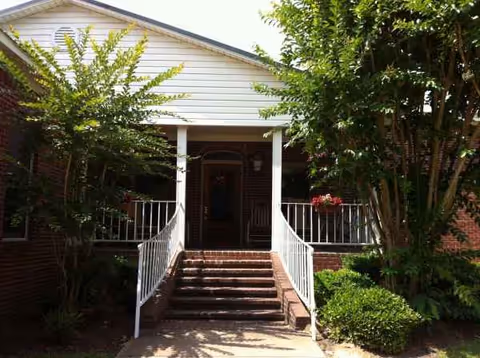 Front entrance of Atwood Personal Care Home, a brick building with steps and white railings.