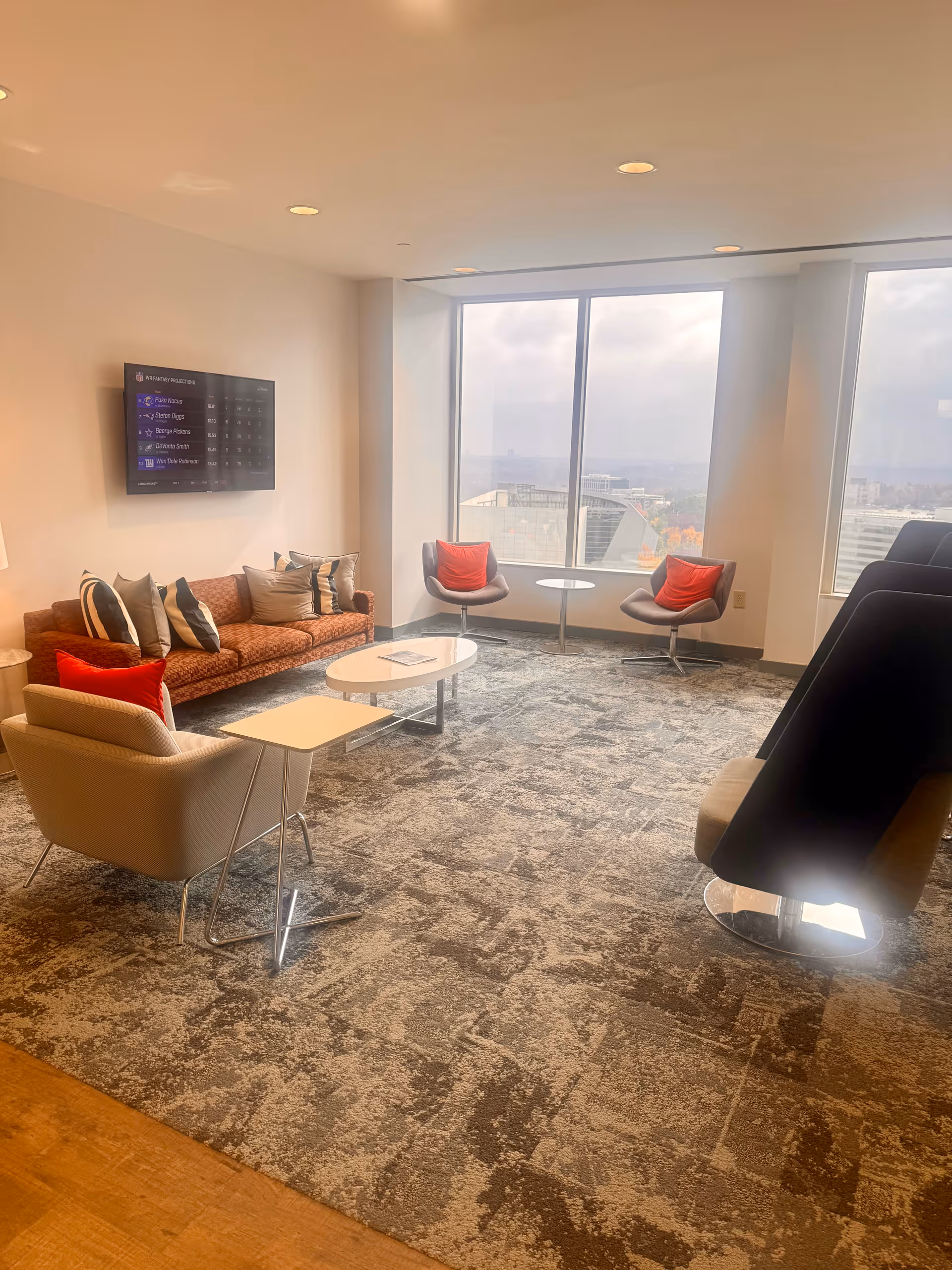 Modern senior living lounge with sofas, chairs, and large windows overlooking the city