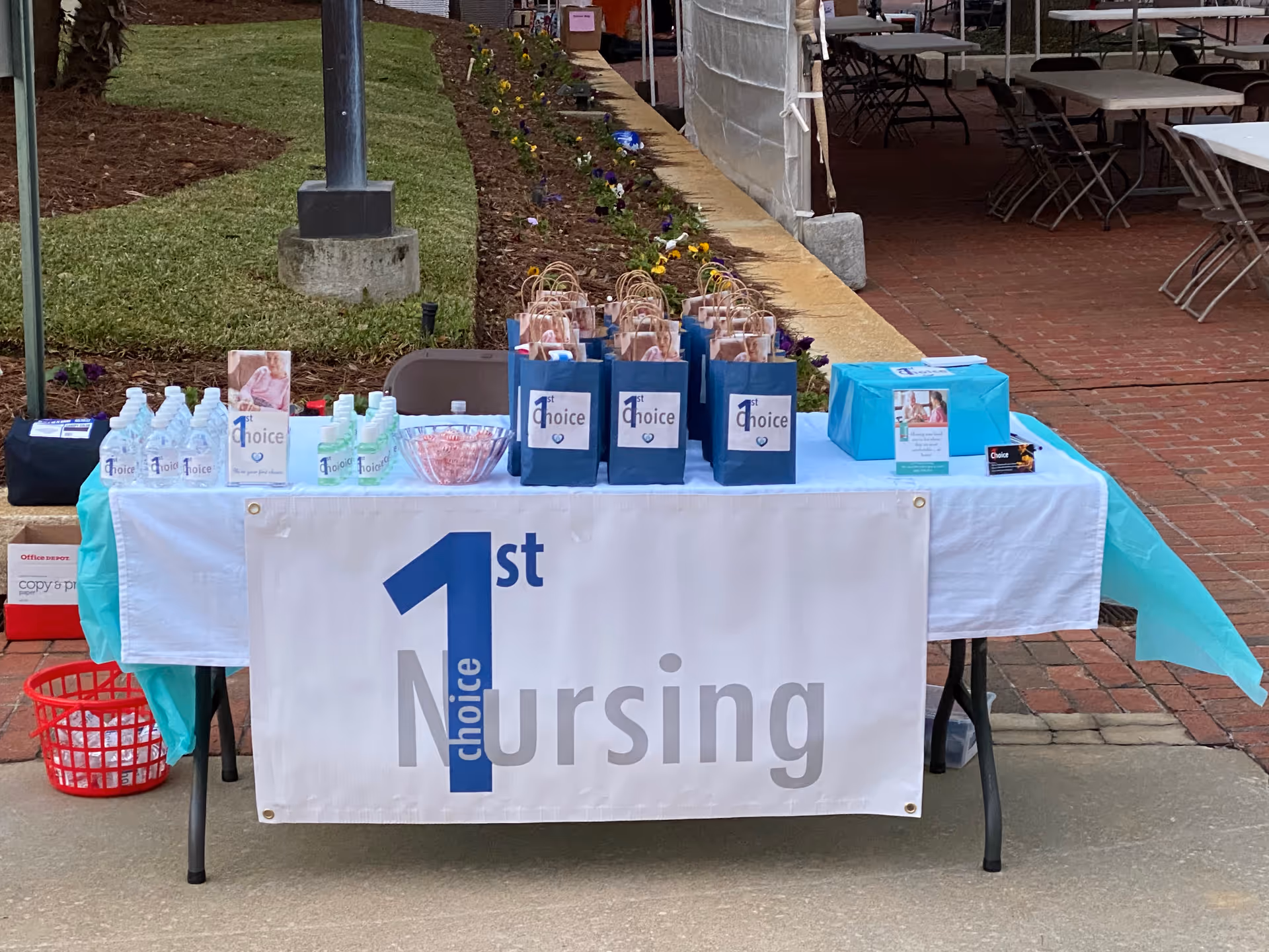 Outdoor table displaying 1st Choice Nursing promotional bags and supplies.
