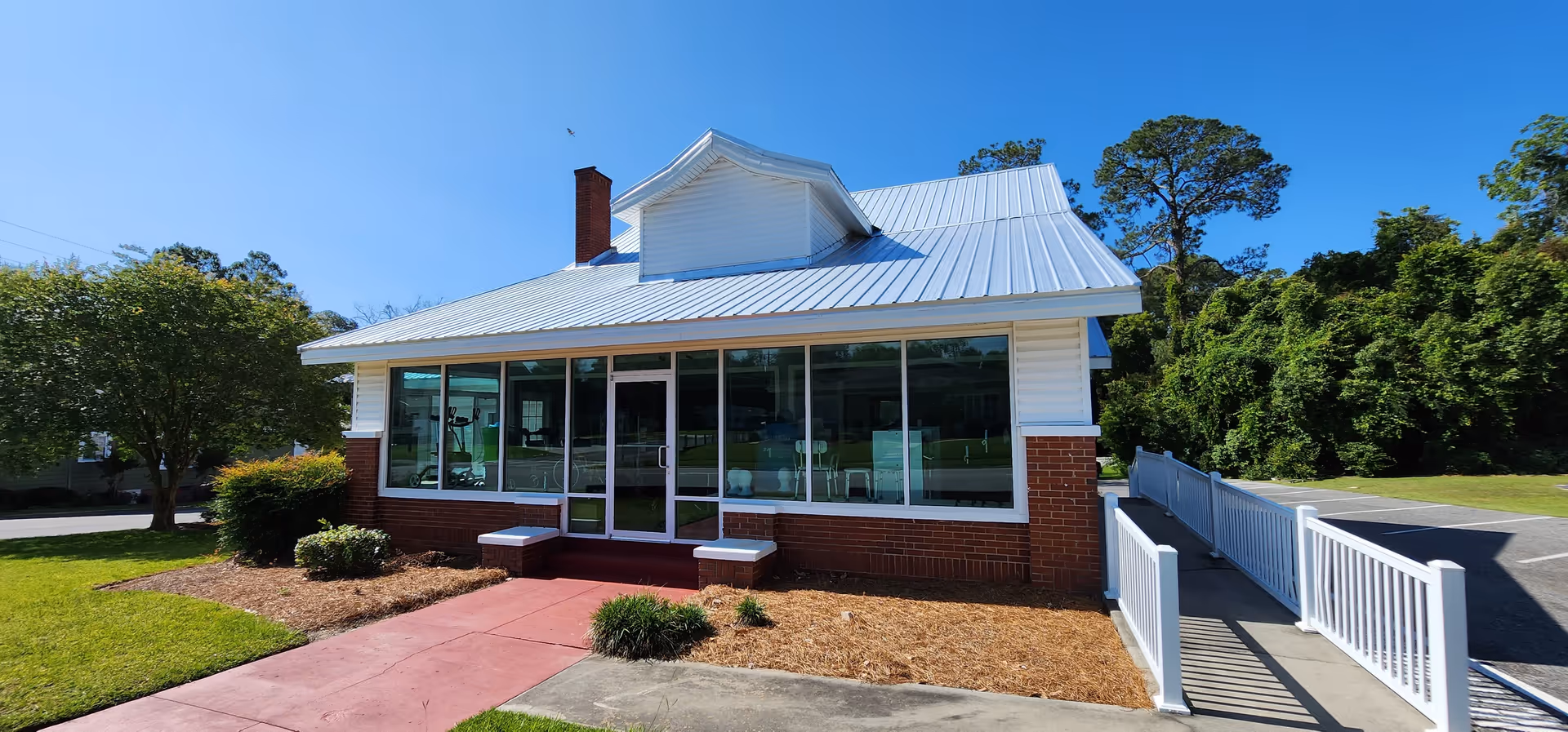 Exterior view of a senior living facility with glass front and ramp.