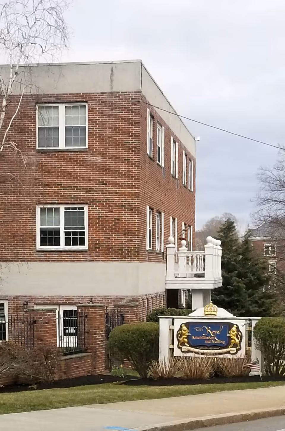 Exterior view of Royal Health Braintree's brick building with a decorative sign and landscaping.