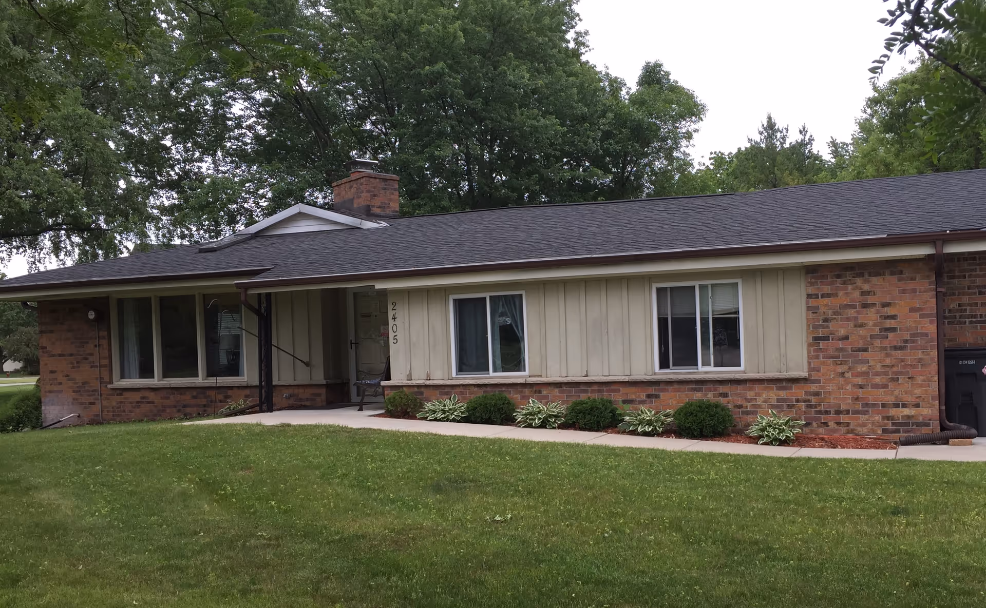 One-story brick and siding senior living facility front with windows and a green lawn.
