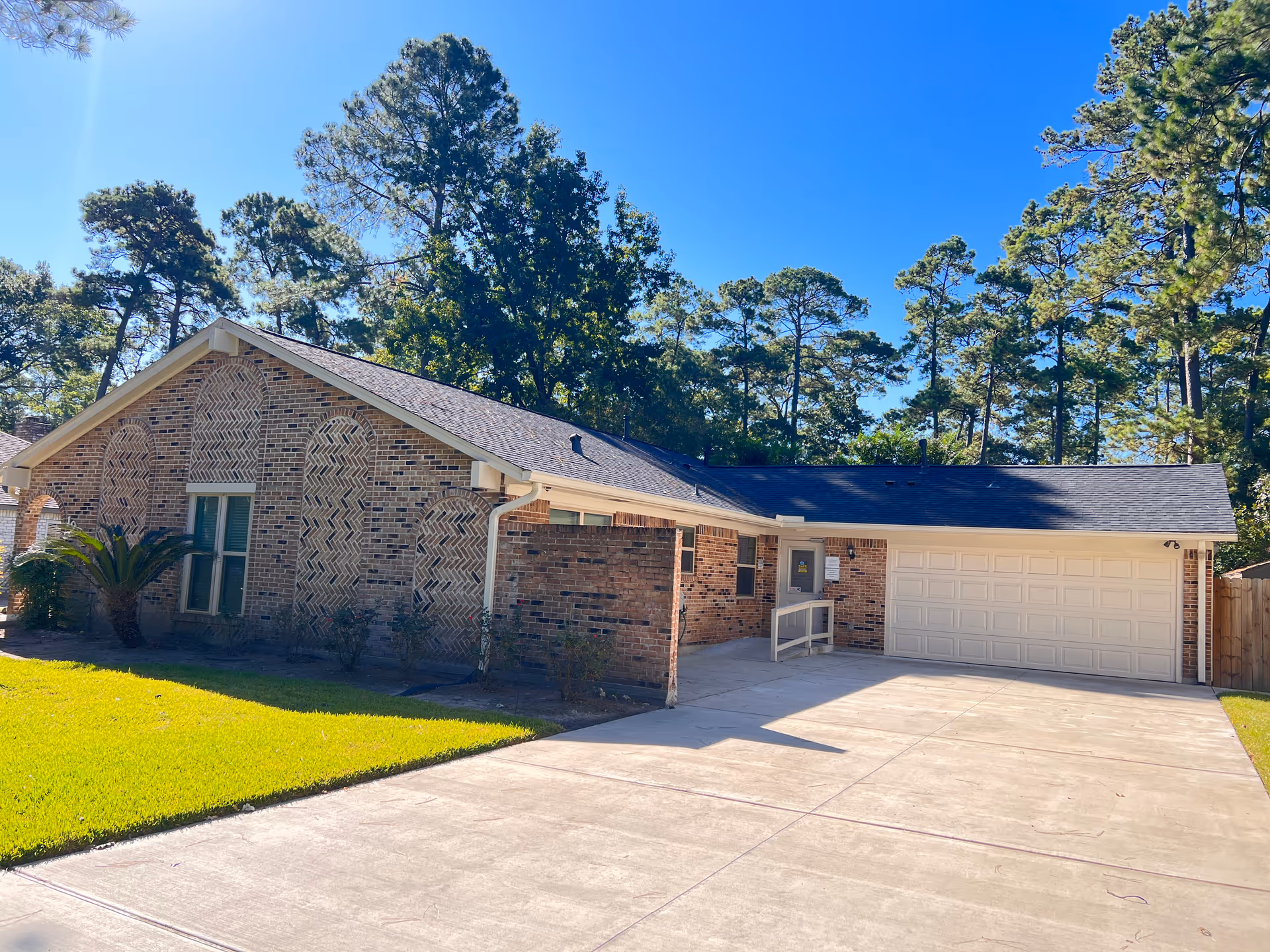 Brick, single-story facility with a two-car garage, driveway, and green lawn.