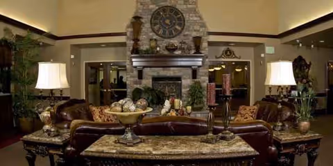 Cozy Pine View Transitional Rehab lounge featuring a stone fireplace, leather sofas, coffee table, and decor.