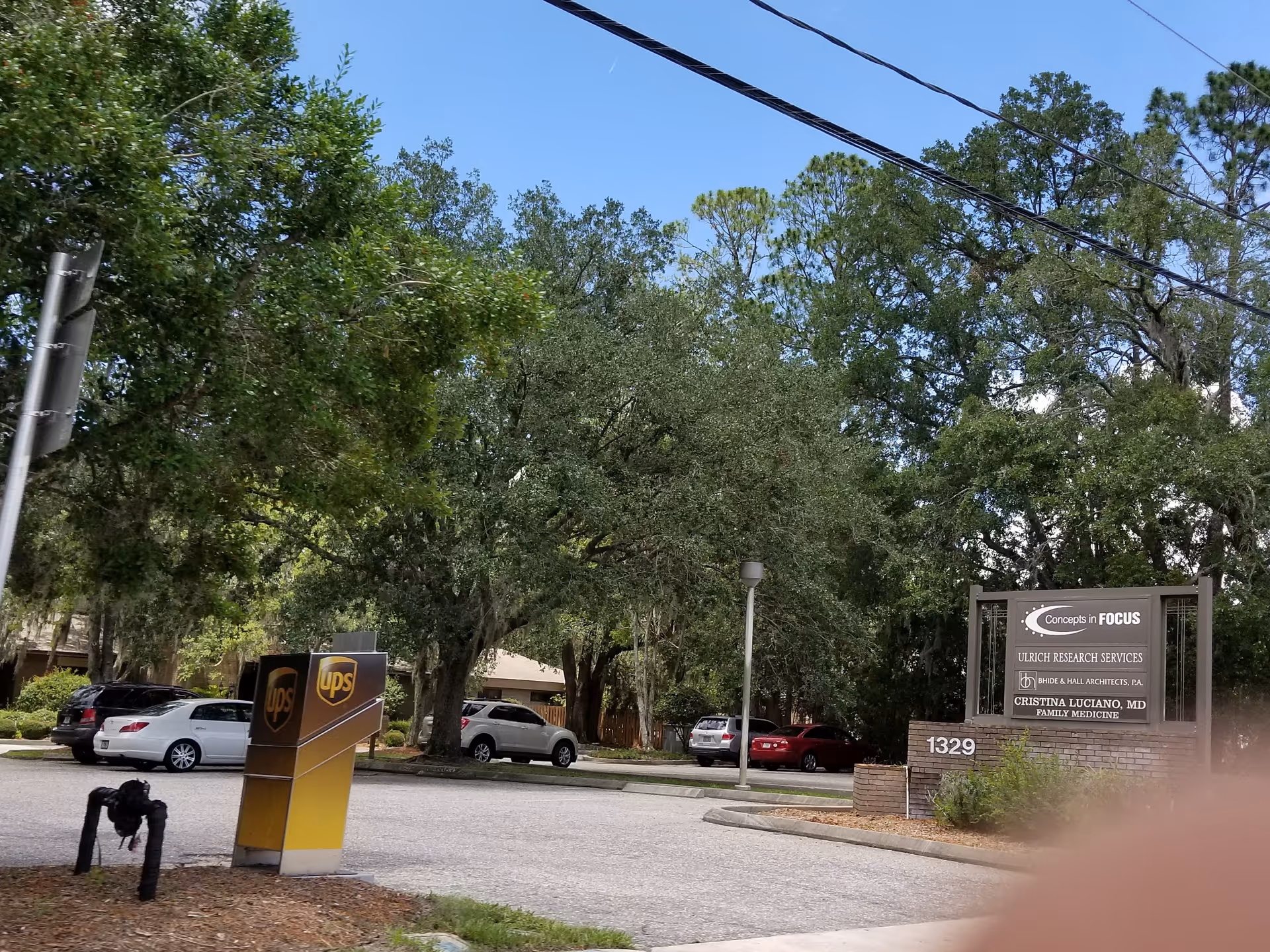 Exterior view of Brooks Rehabilitation Home Health Orange Park with trees, signage, and parked cars.