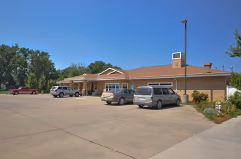 Exterior view of Windsor Manor senior living facility with parked cars in the lot.