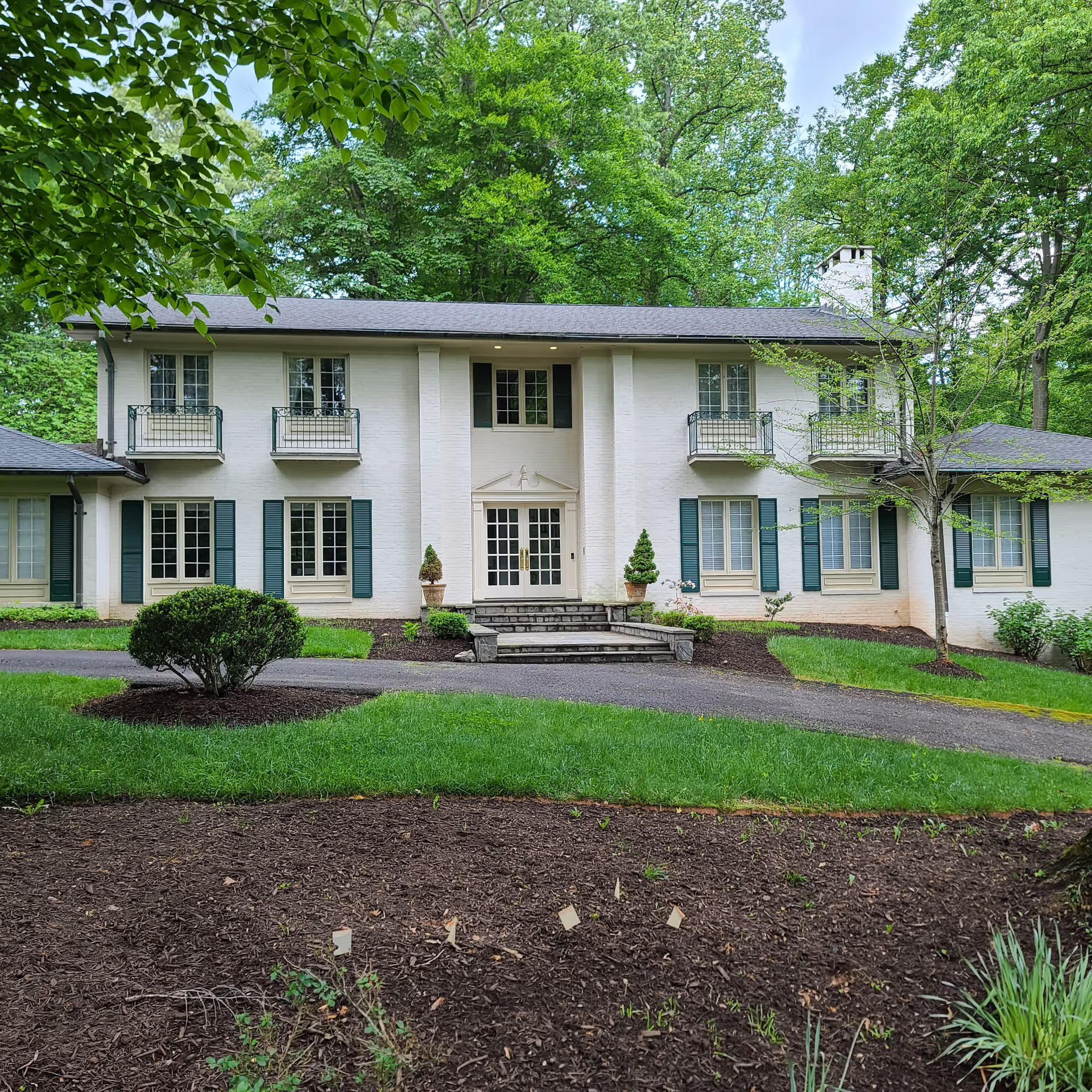 Westmont House exterior: a white two-story senior living facility with green shutters and landscaped grounds.