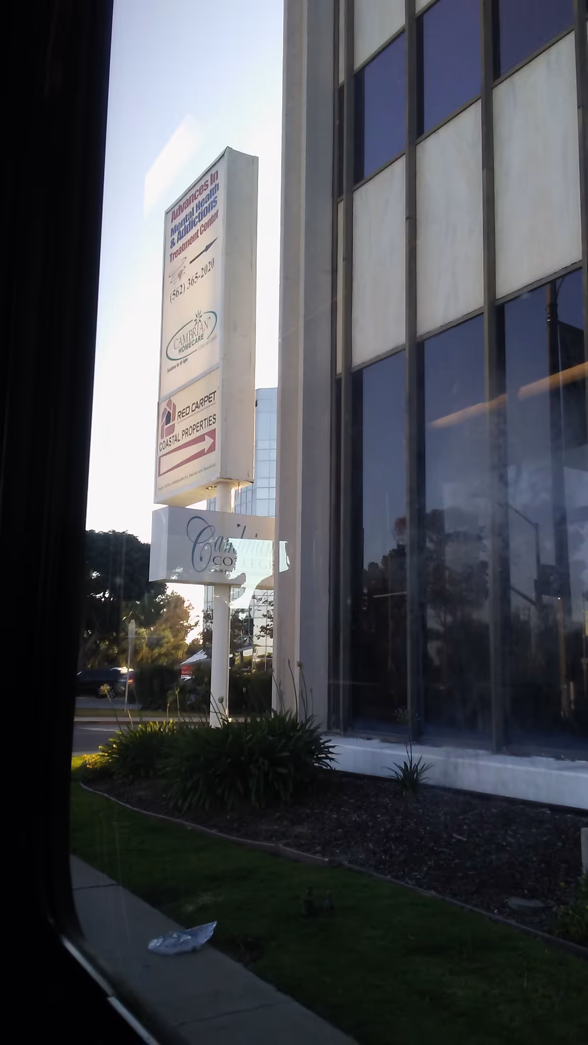 Tall exterior sign outside a modern building shows Cambrian Homecare signage and glass storefront.