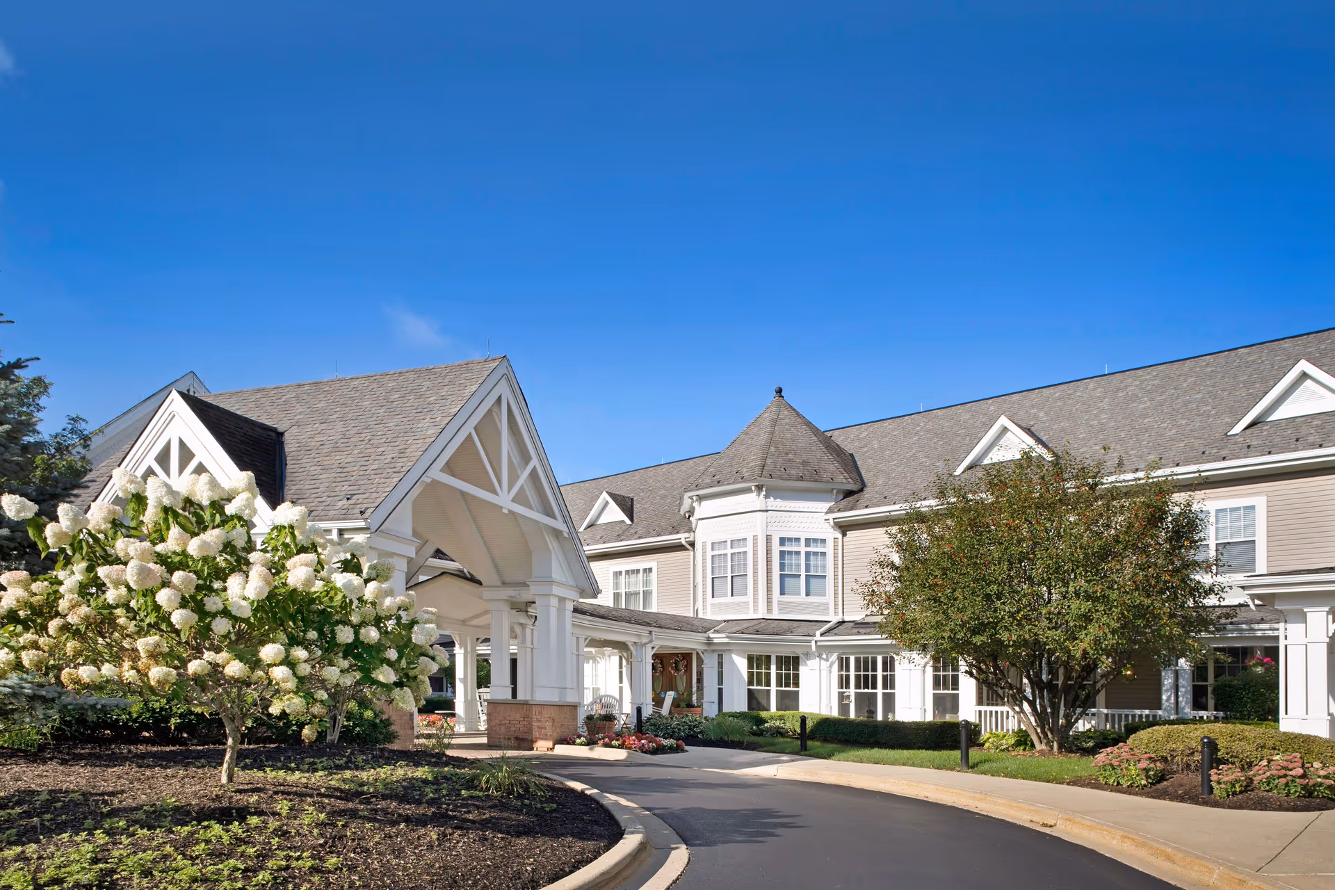 Sunny entrance to Sunrise of Crystal Lake senior living facility with landscaped grounds