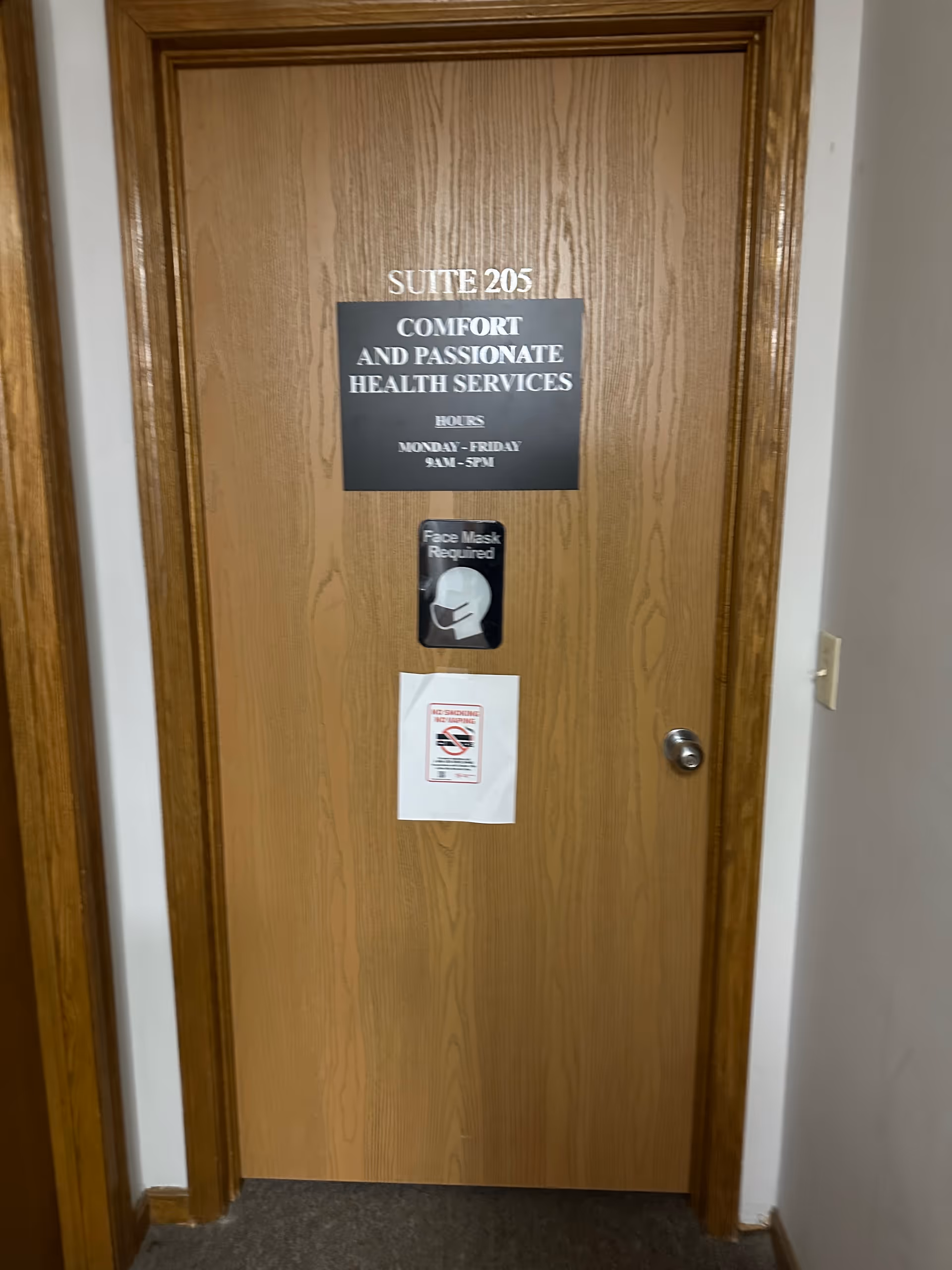 Wooden interior door displaying Suite 205 and Comfort and Passionate Health Services signage.