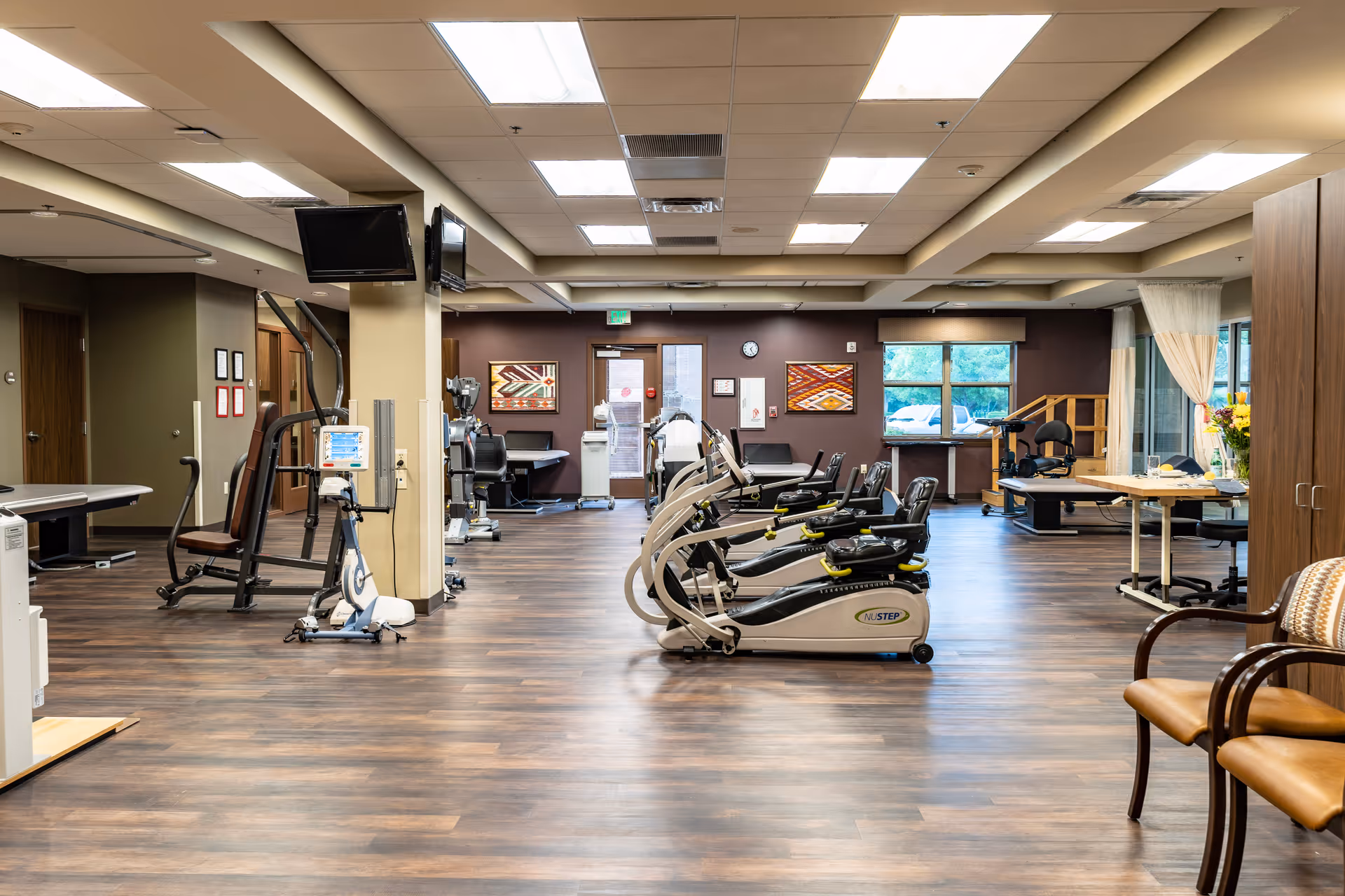 Indoor senior fitness center with treadmills, bikes, and elliptical machines in a bright spacious room.