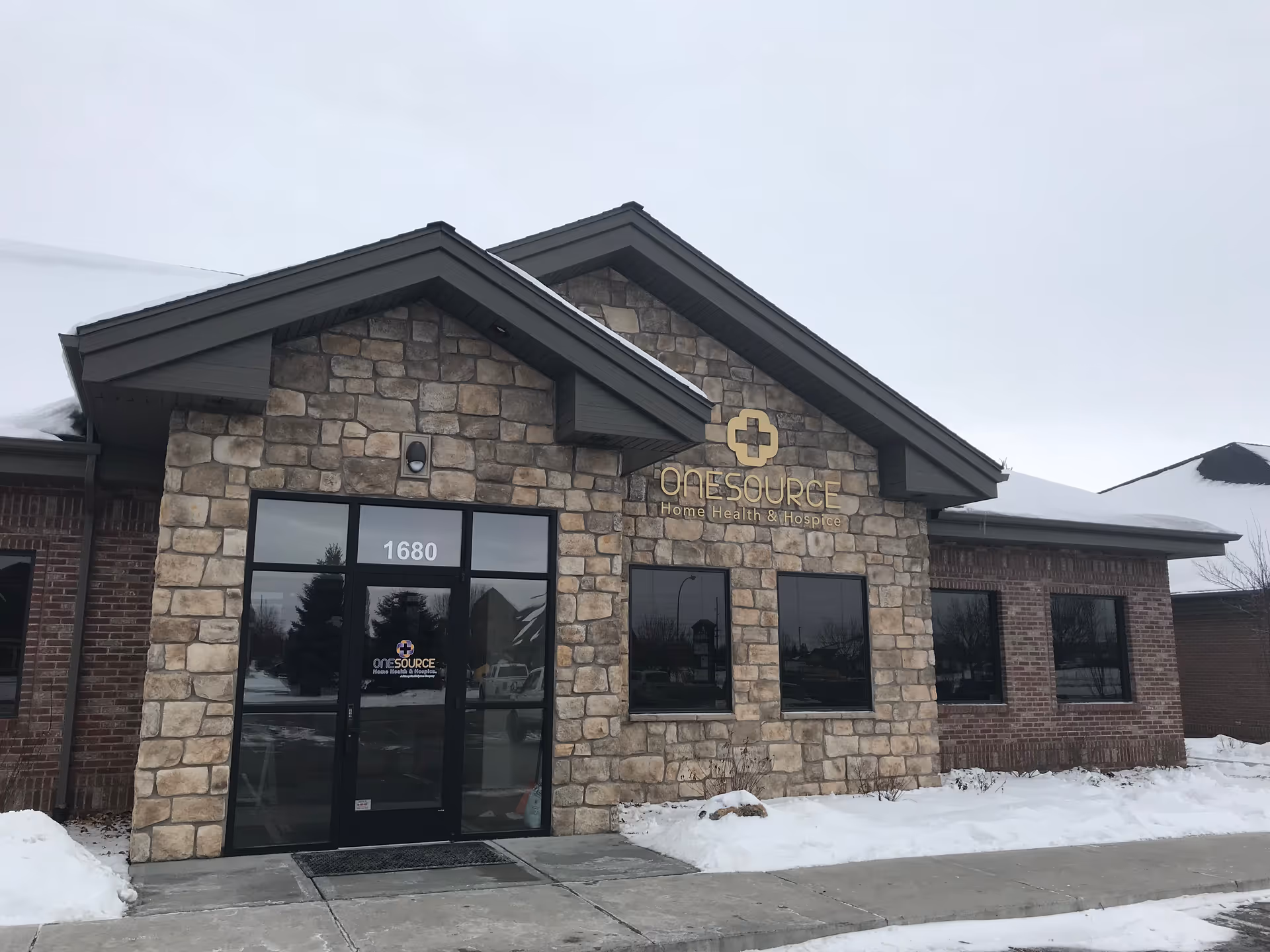 Stone-front building with OneSource sign and glass entrance on a snowy day
