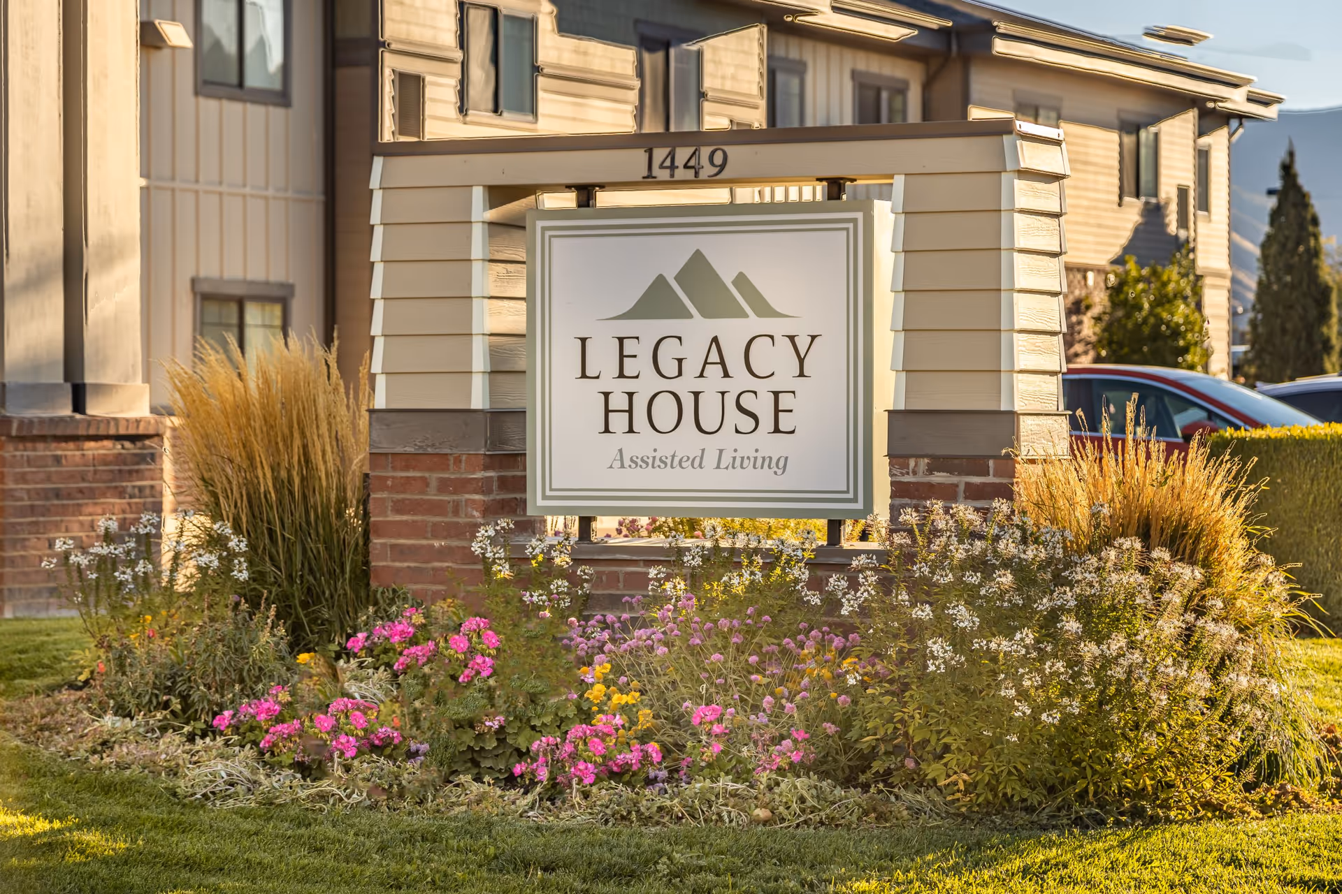 A landscaped entrance sign that reads "Legacy House Assisted Living" in front of the facility.