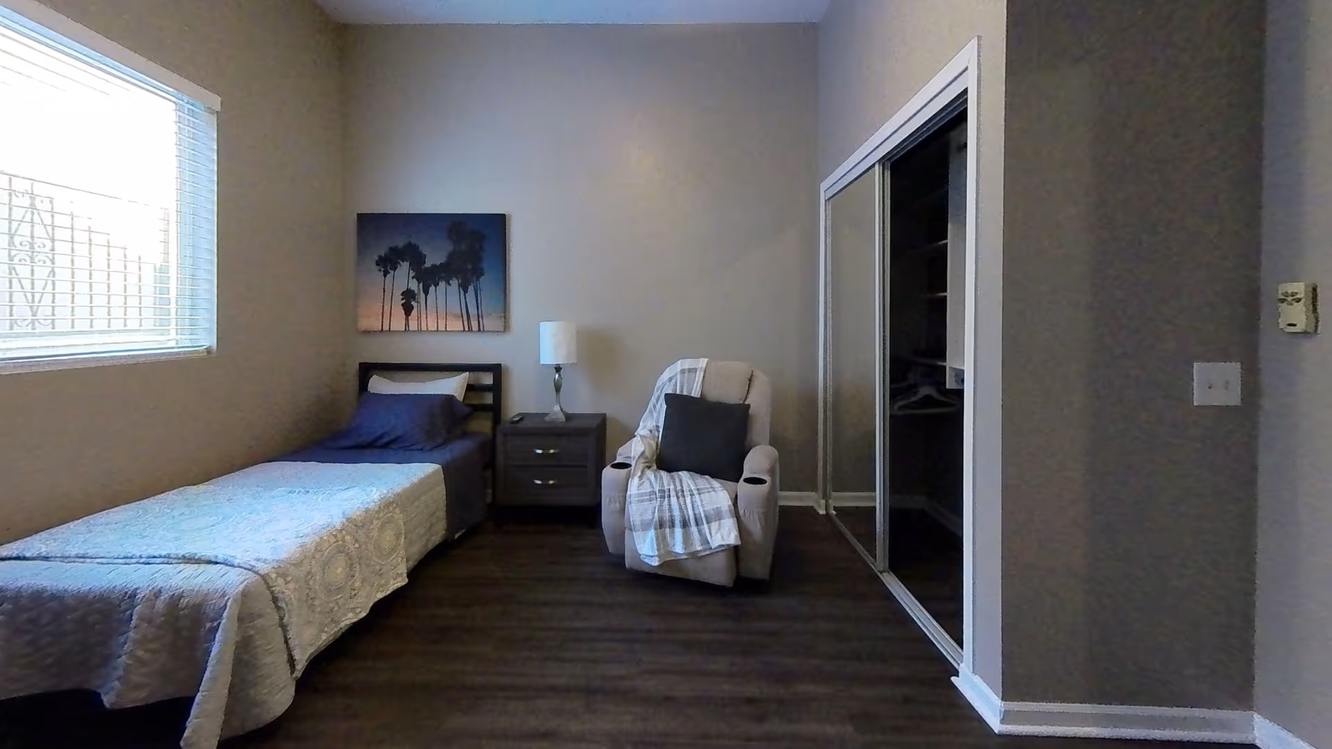 This is a cozy senior living bedroom with a single bed, recliner, nightstand, and closet.