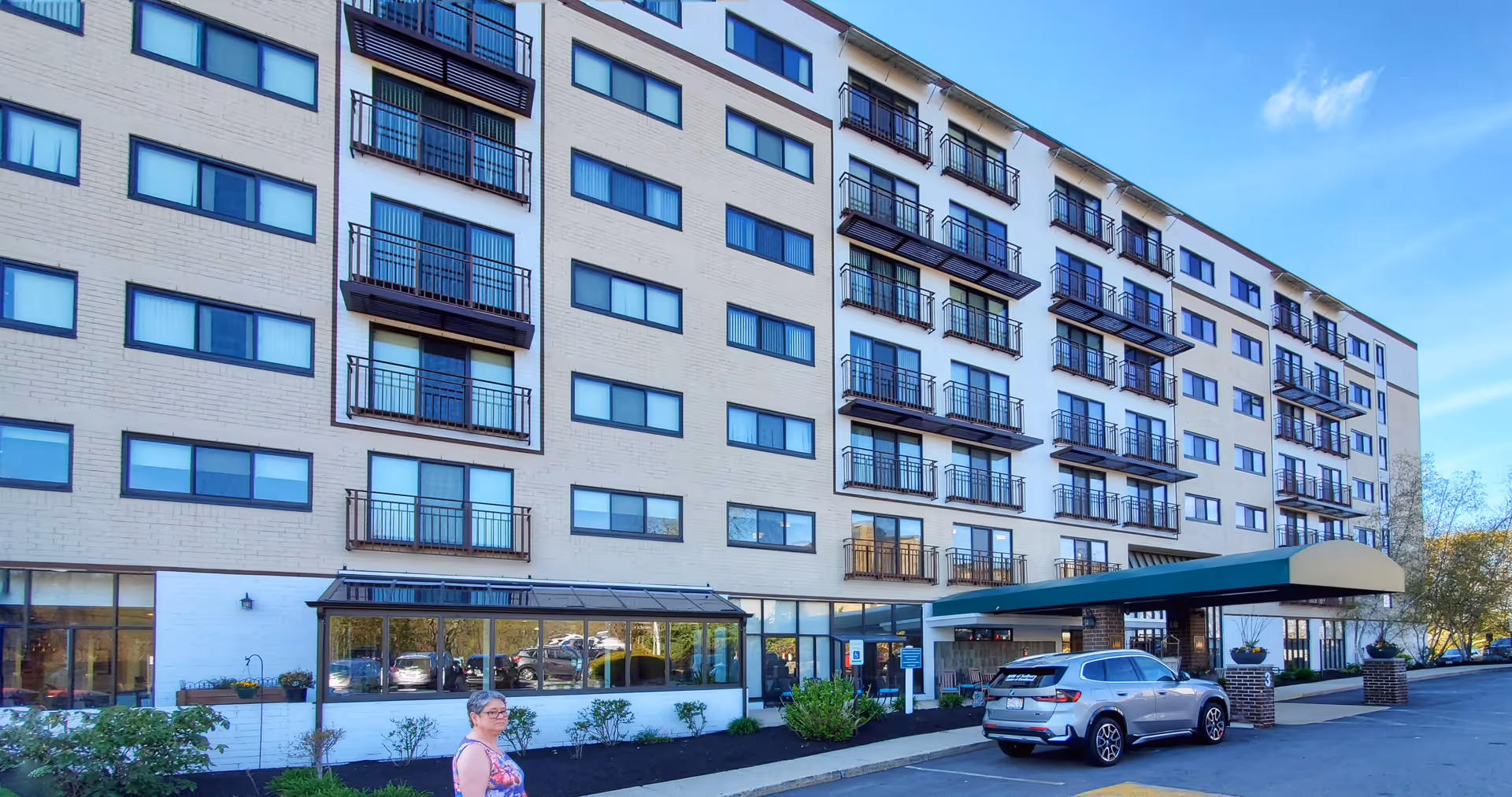A multi-story senior living facility with balconies, large windows, and a covered entrance.
