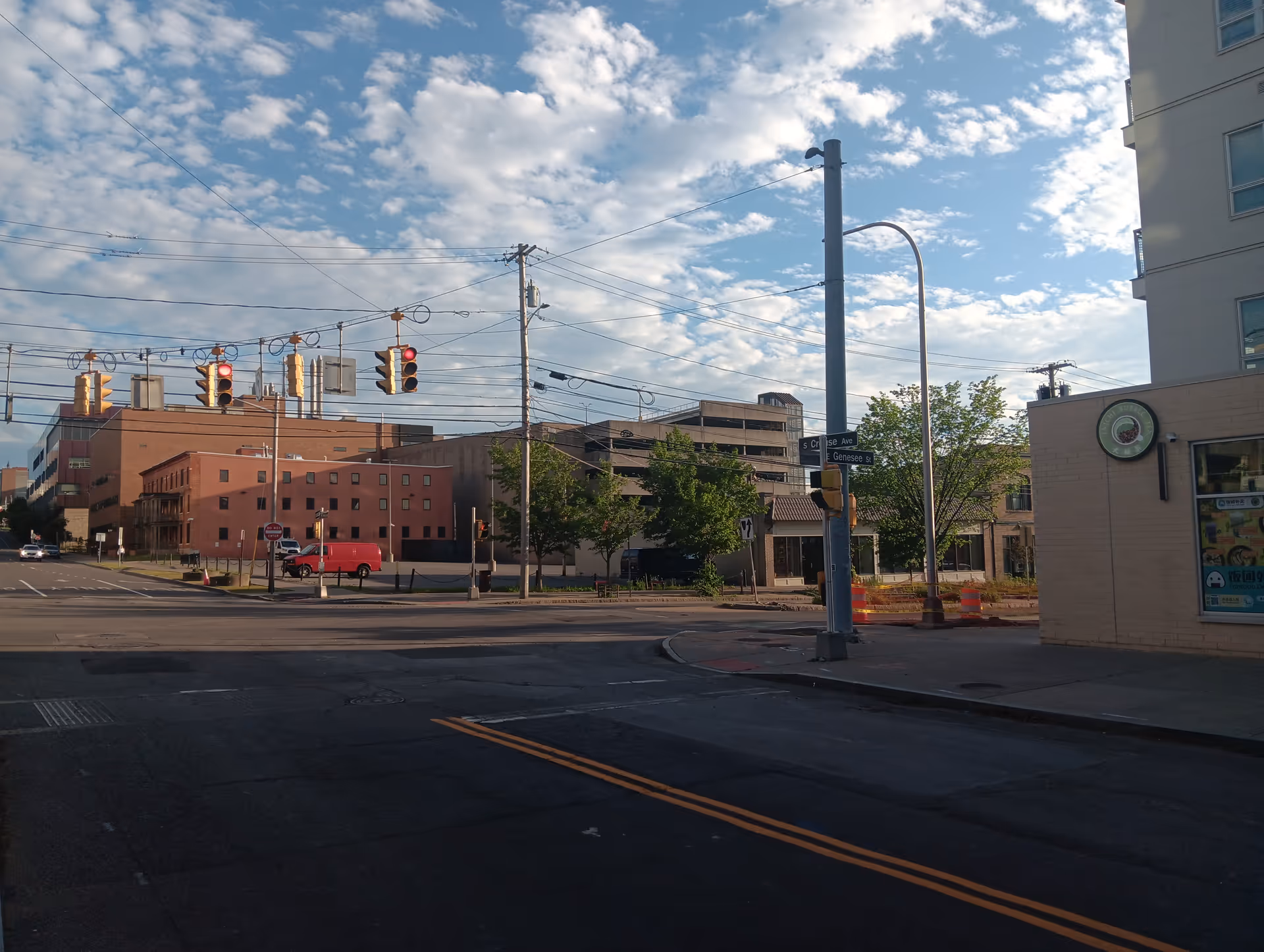 Urban street scene with traffic signals, crosswalks, and a modern building exterior.