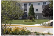 Exterior view of Creekwood senior living building with green lawns and trees.