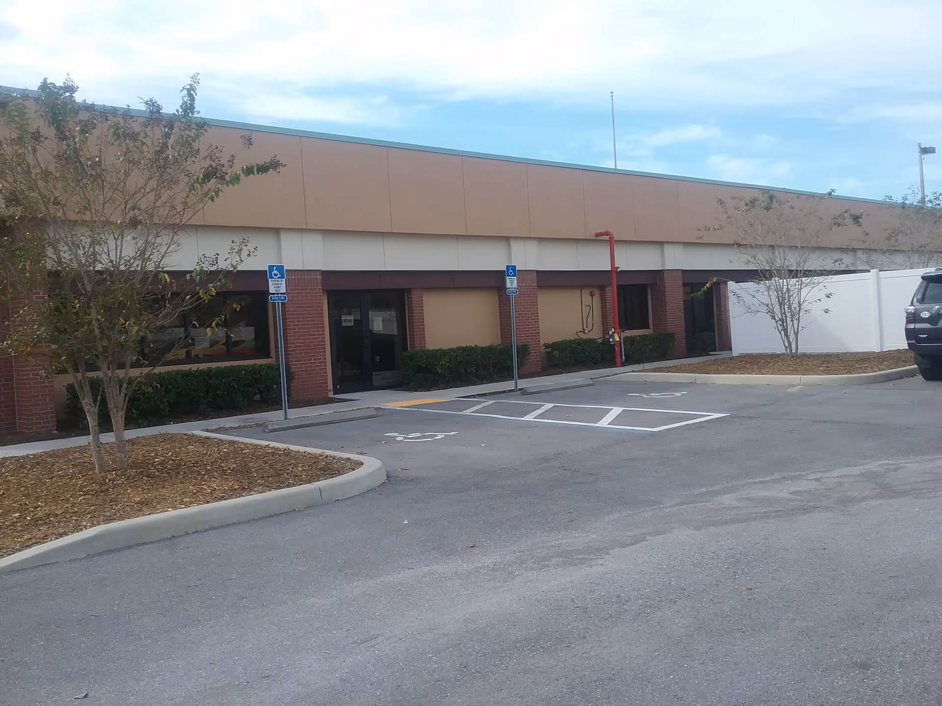 Front exterior of Comfort Keepers facility in Dunedin with parking lot and handicap spots