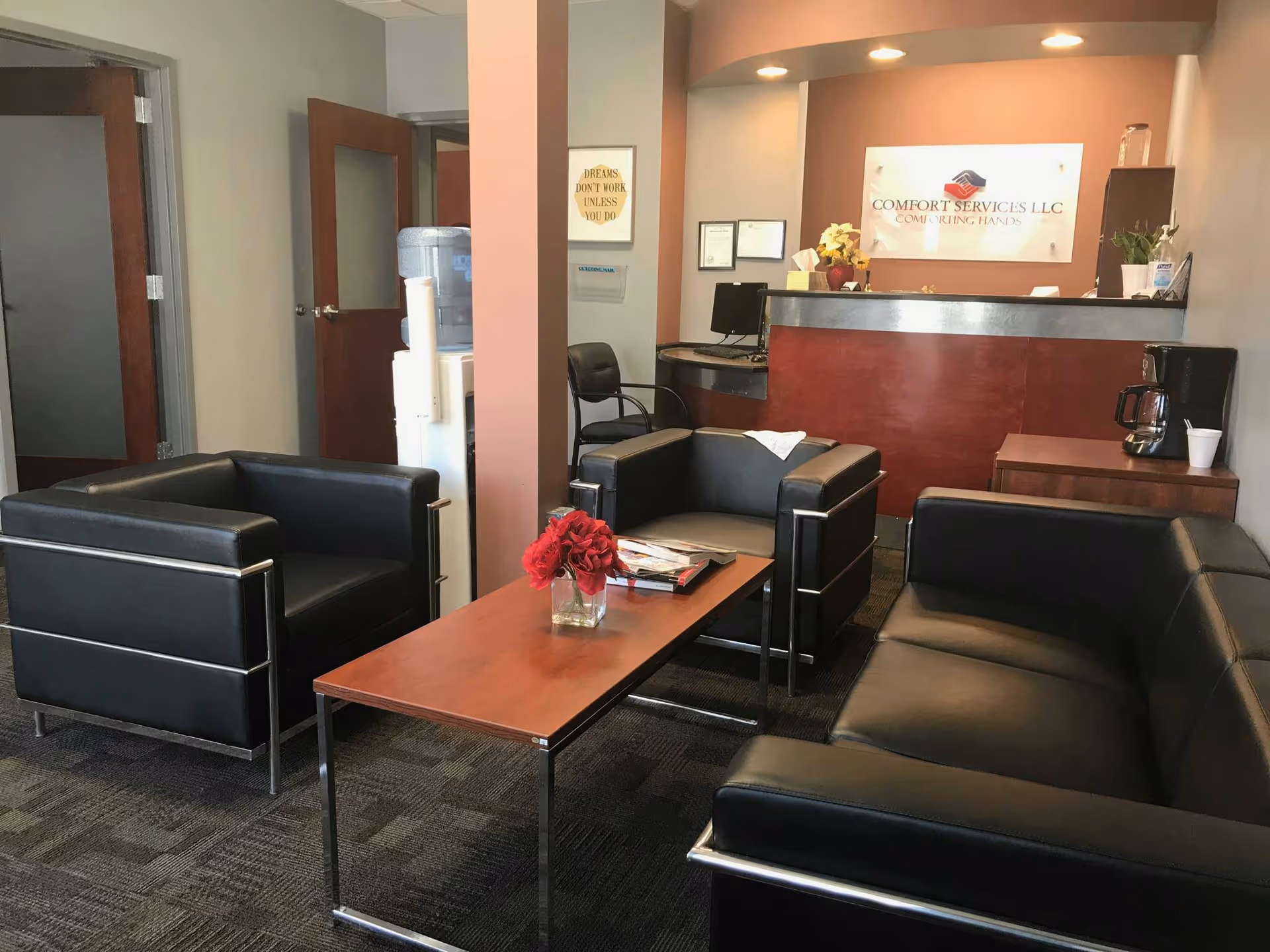 Modern waiting area with black leather seating, coffee table, and reception desk displaying Comfort Services LLC.