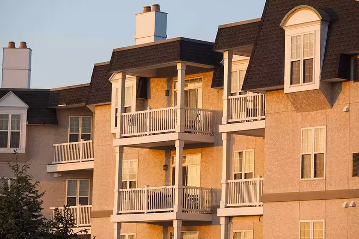 Exterior view of a multi-story senior living building with white balconies and dormer windows.