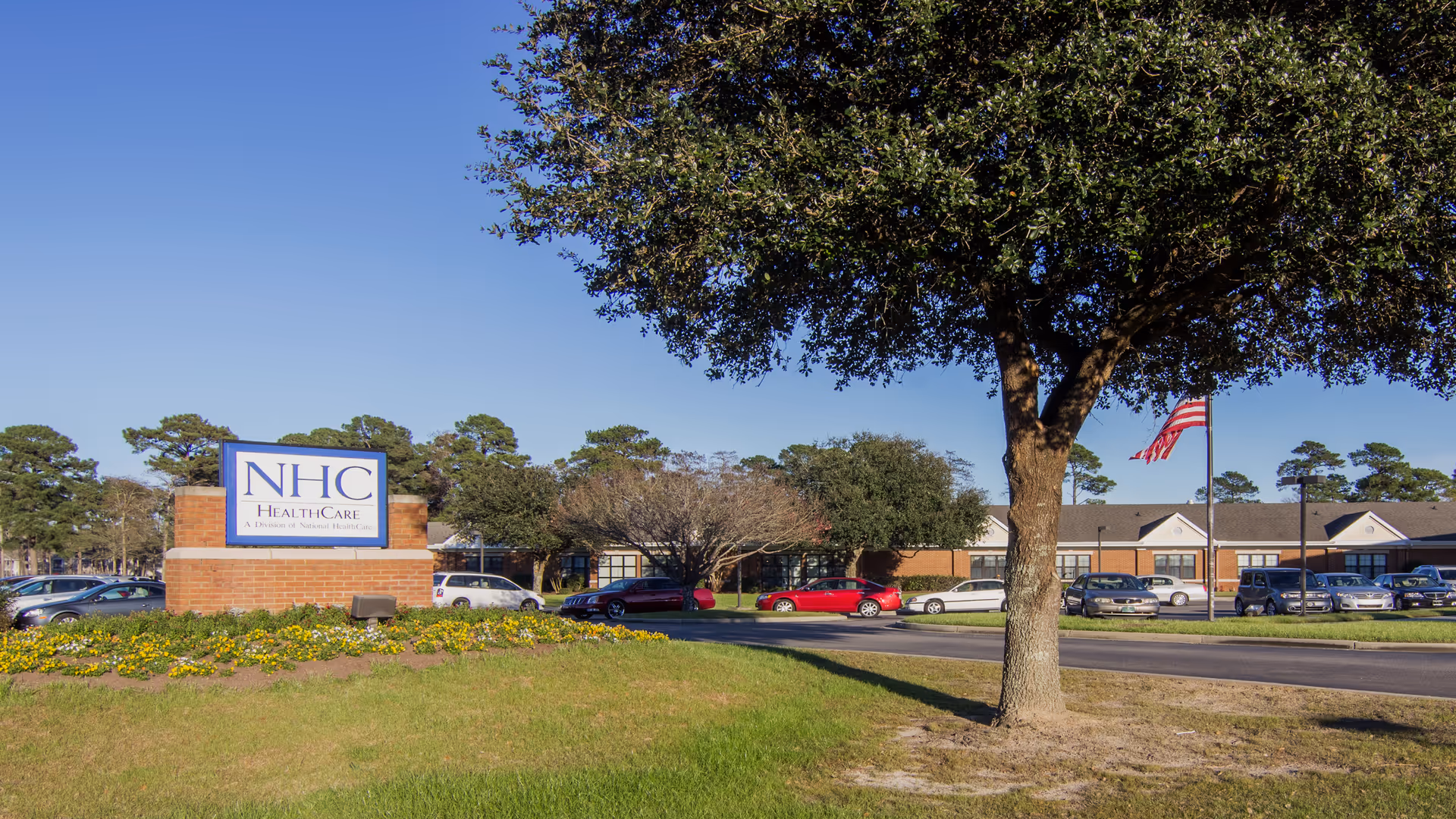 NHC HealthCare Garden City exterior with sign, landscaping, and parked cars.
