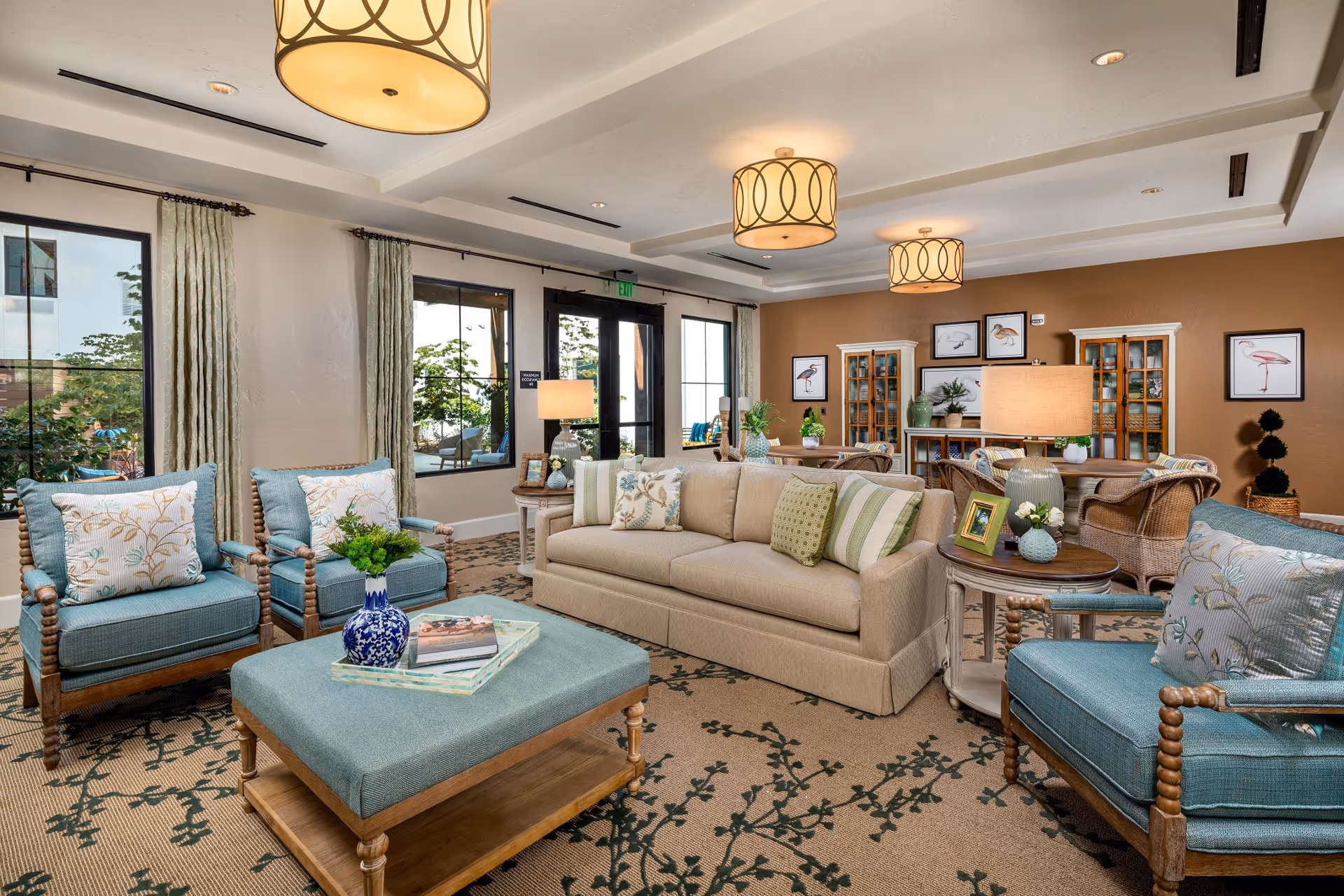 Bright senior living lounge with beige sofa, teal chairs, and decorative accents.
