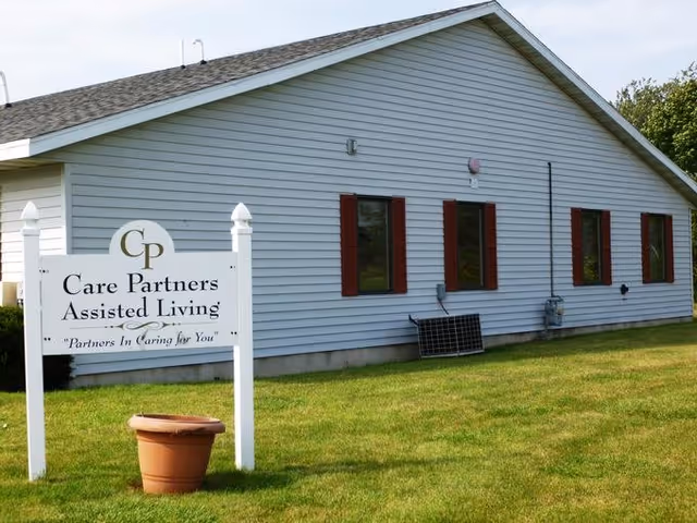 Front exterior of Care Partners Assisted Living with a sign on a grassy lawn.