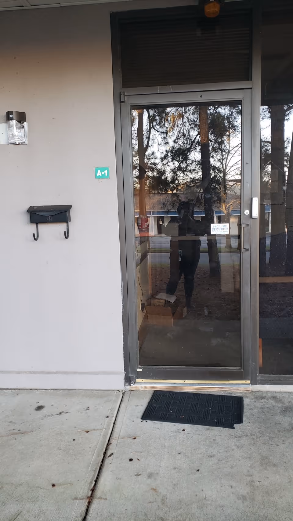 Exterior glass door with reflection, mailbox, and concrete entrance.