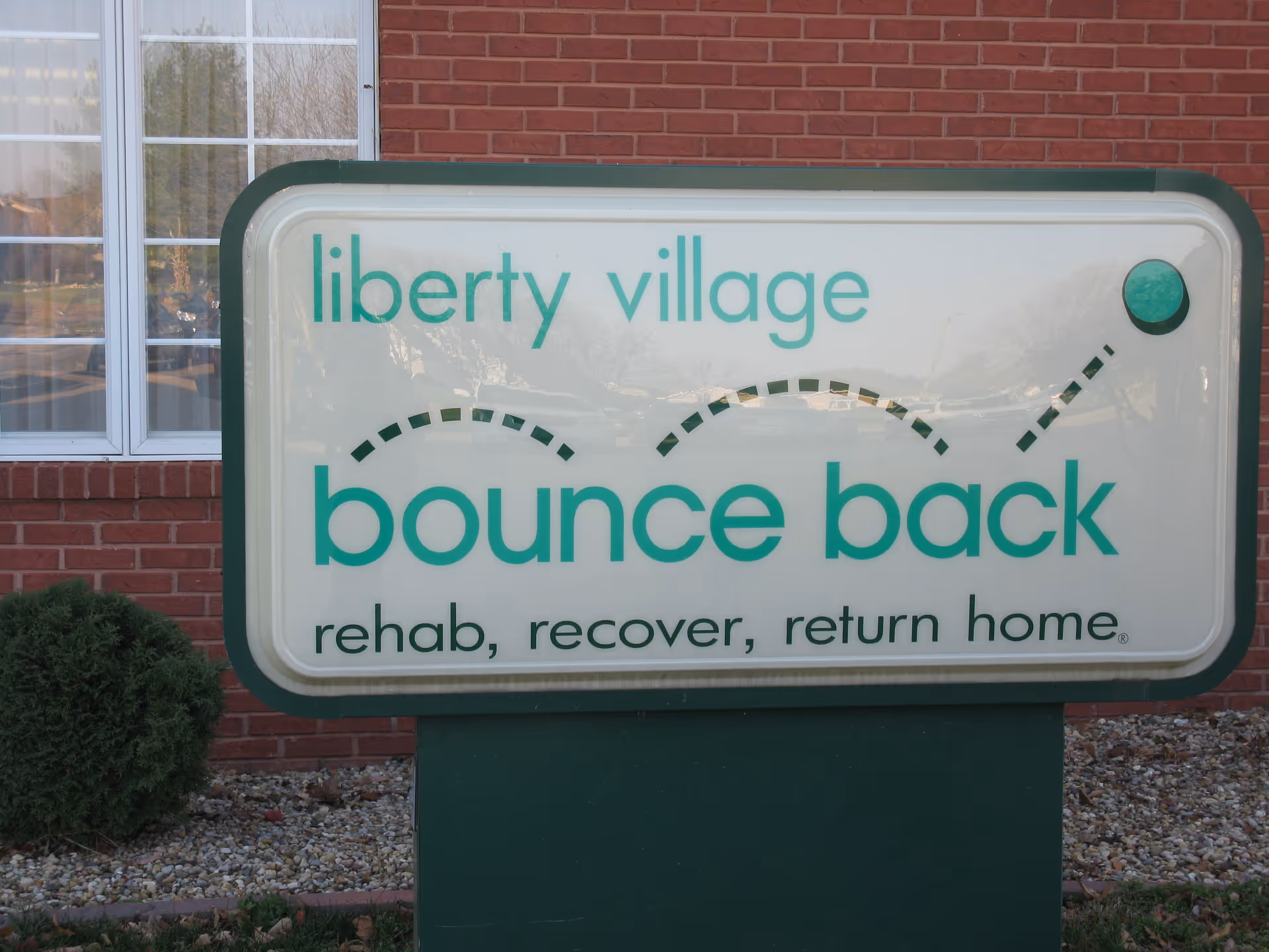 A large sign reading Liberty Village bounce back sits in front of a brick building.