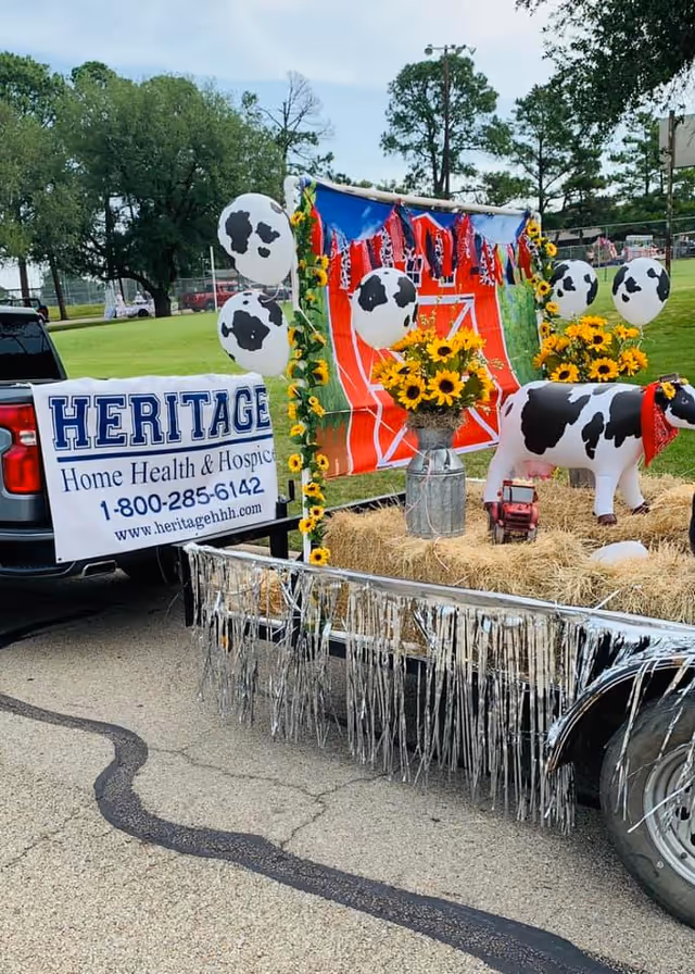 Heritage Home Health & Hospice parade float with sunflowers and cow figures.