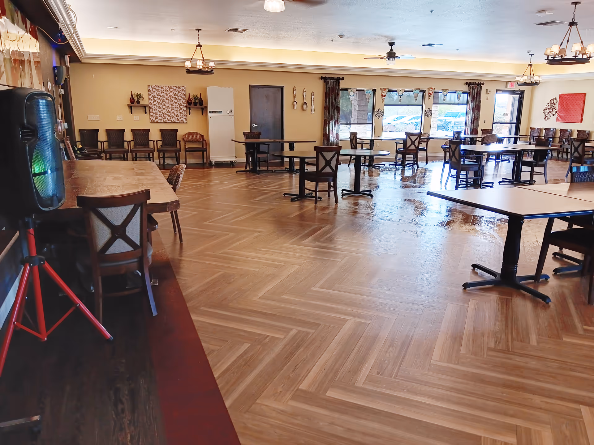 A spacious indoor dining room with numerous tables and chairs in a senior living facility.