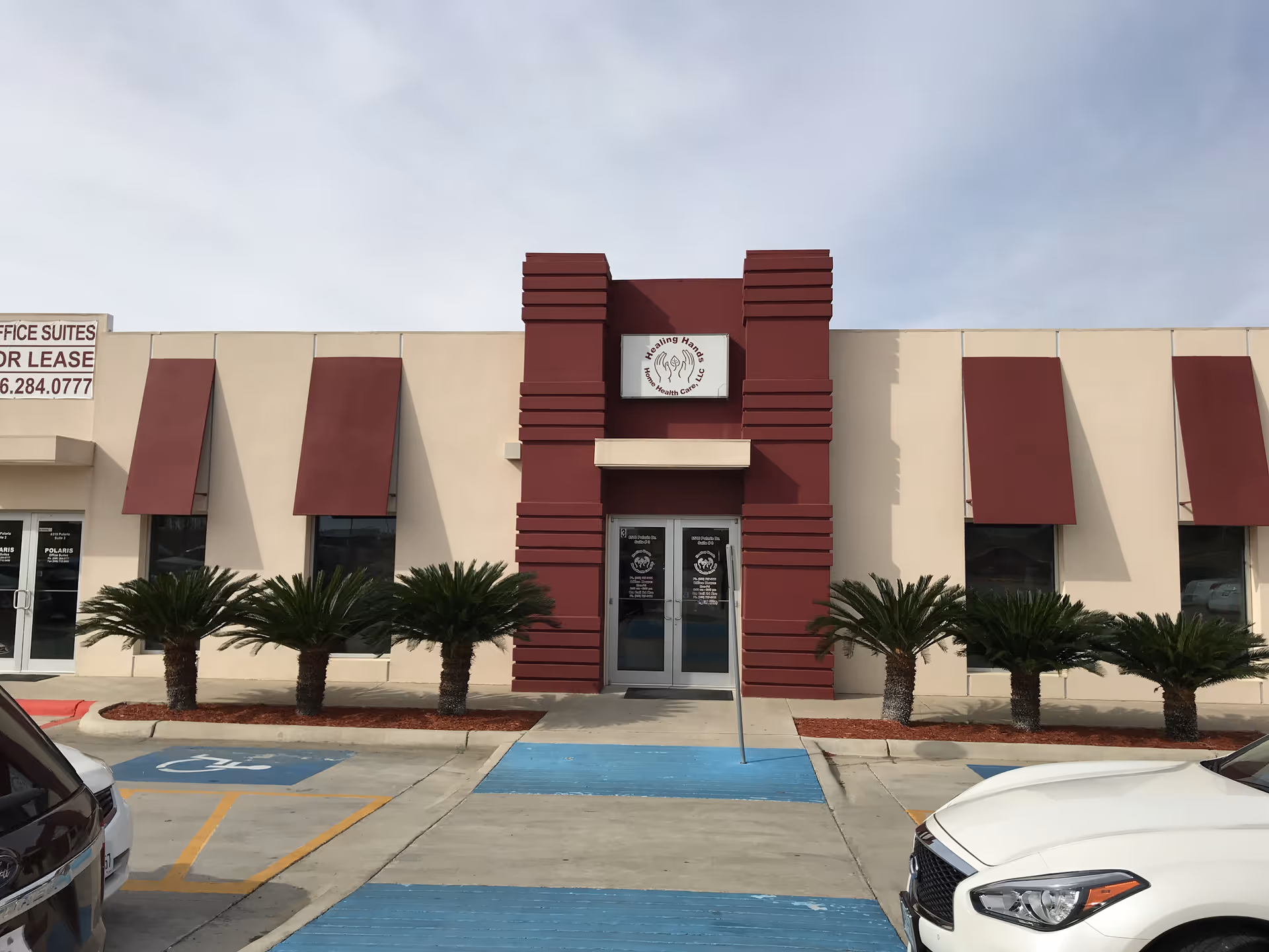 Exterior view of Healing Hands facility with maroon accents, entrance, and palm trees.