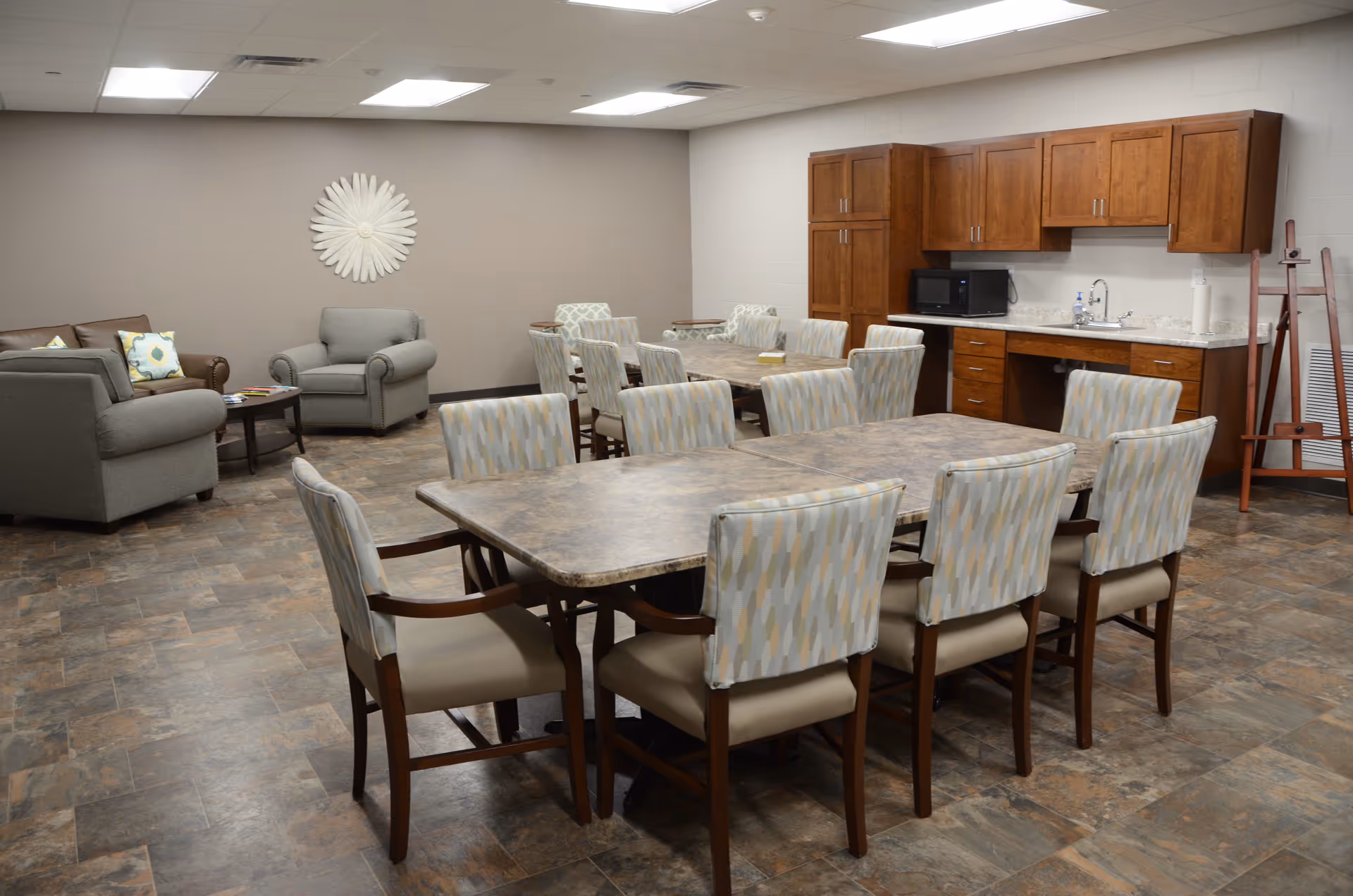 Large communal room with a long dining table, chairs, sofa seating, and a kitchenette.
