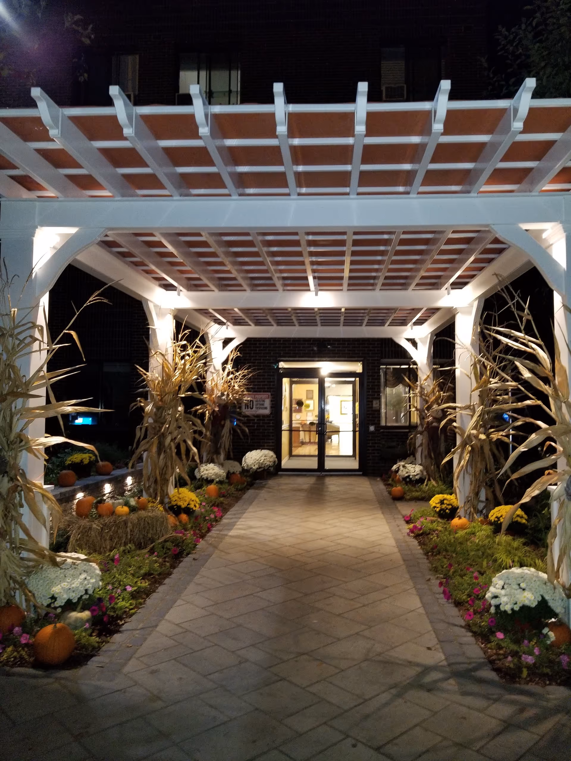Night view of the CareOne at Northampton entrance with a lit walkway and seasonal decorations.