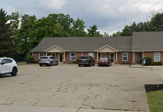 Single-story brick building with multiple entrances and several cars parked in front.