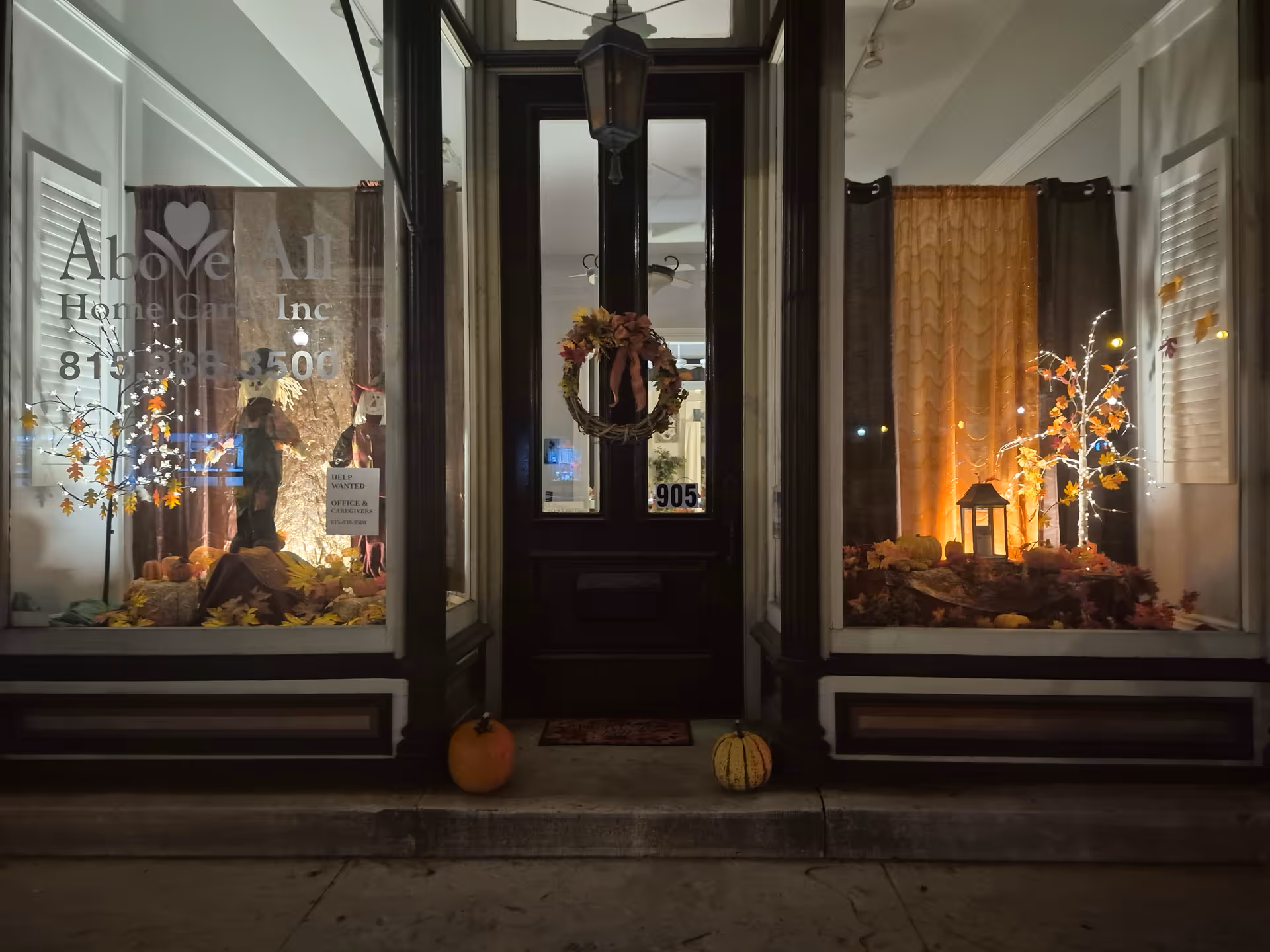 Front view of Above All Home Care storefront with autumn window displays and pumpkins.