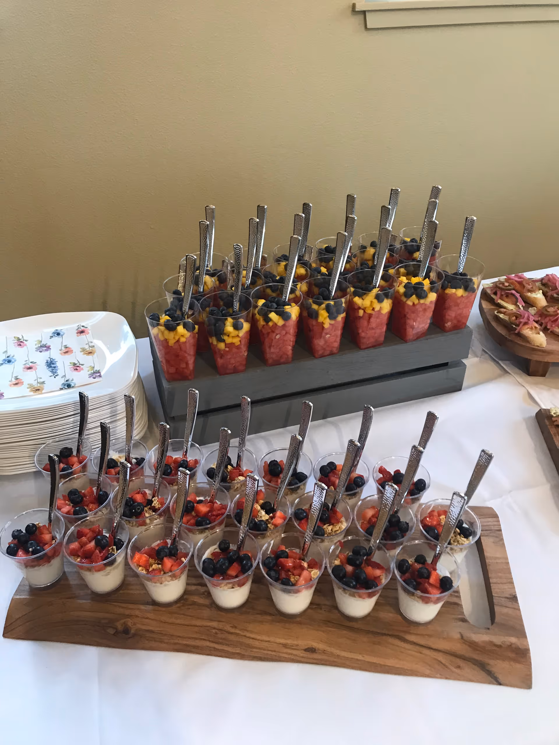 Dessert cups with berries lined up on a buffet table.