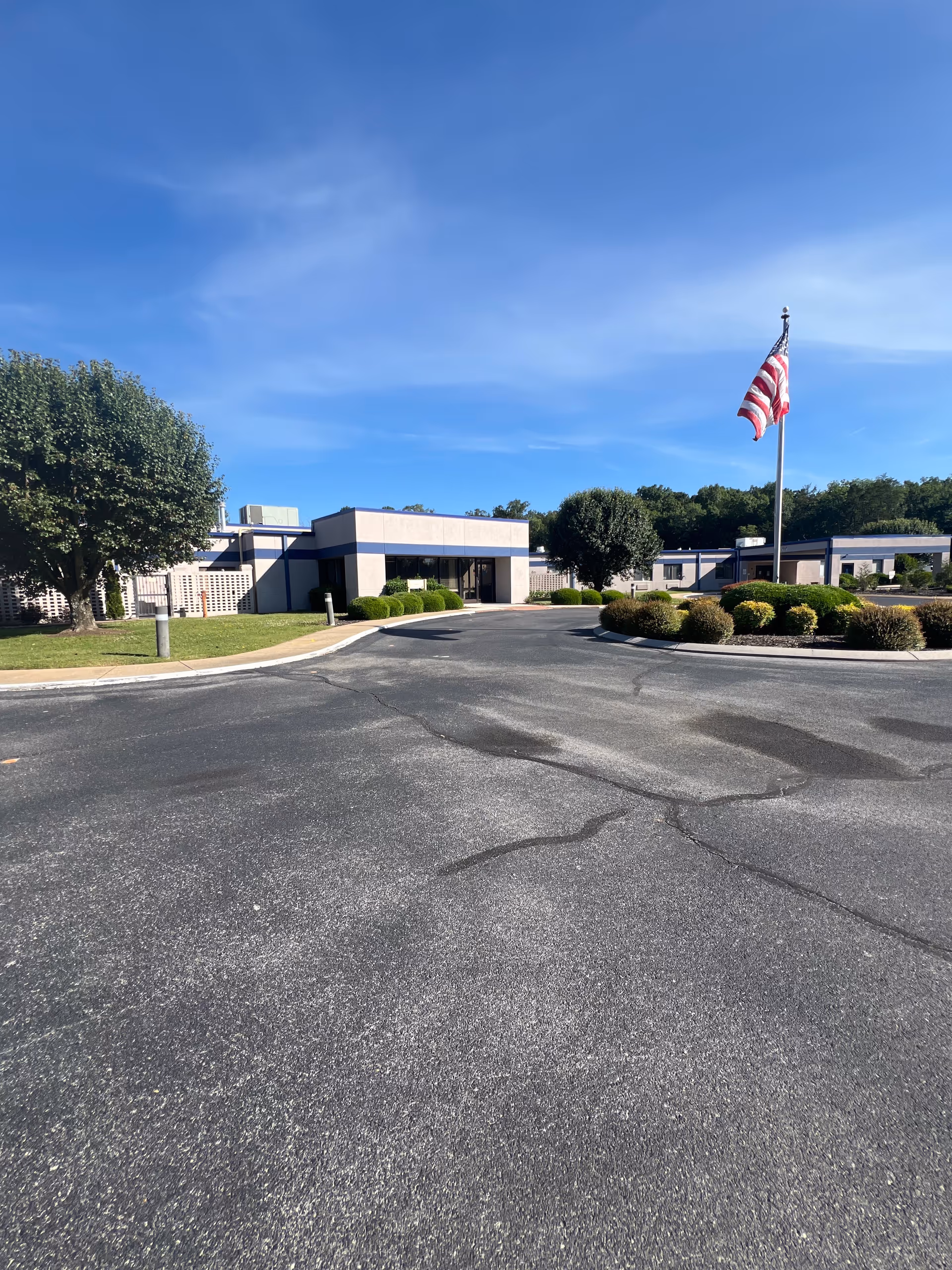 Exterior view of Nhc Healthcare Ft Oglethorpe with flagpole, driveway, and landscaped grounds.